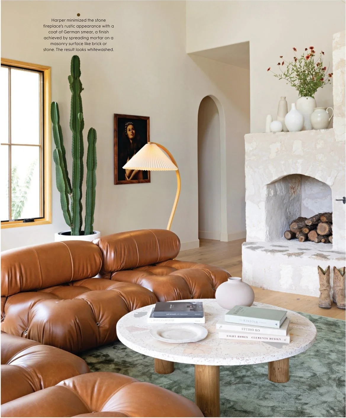 Editorial living room with caramel leather sofa and sculptural fireplace