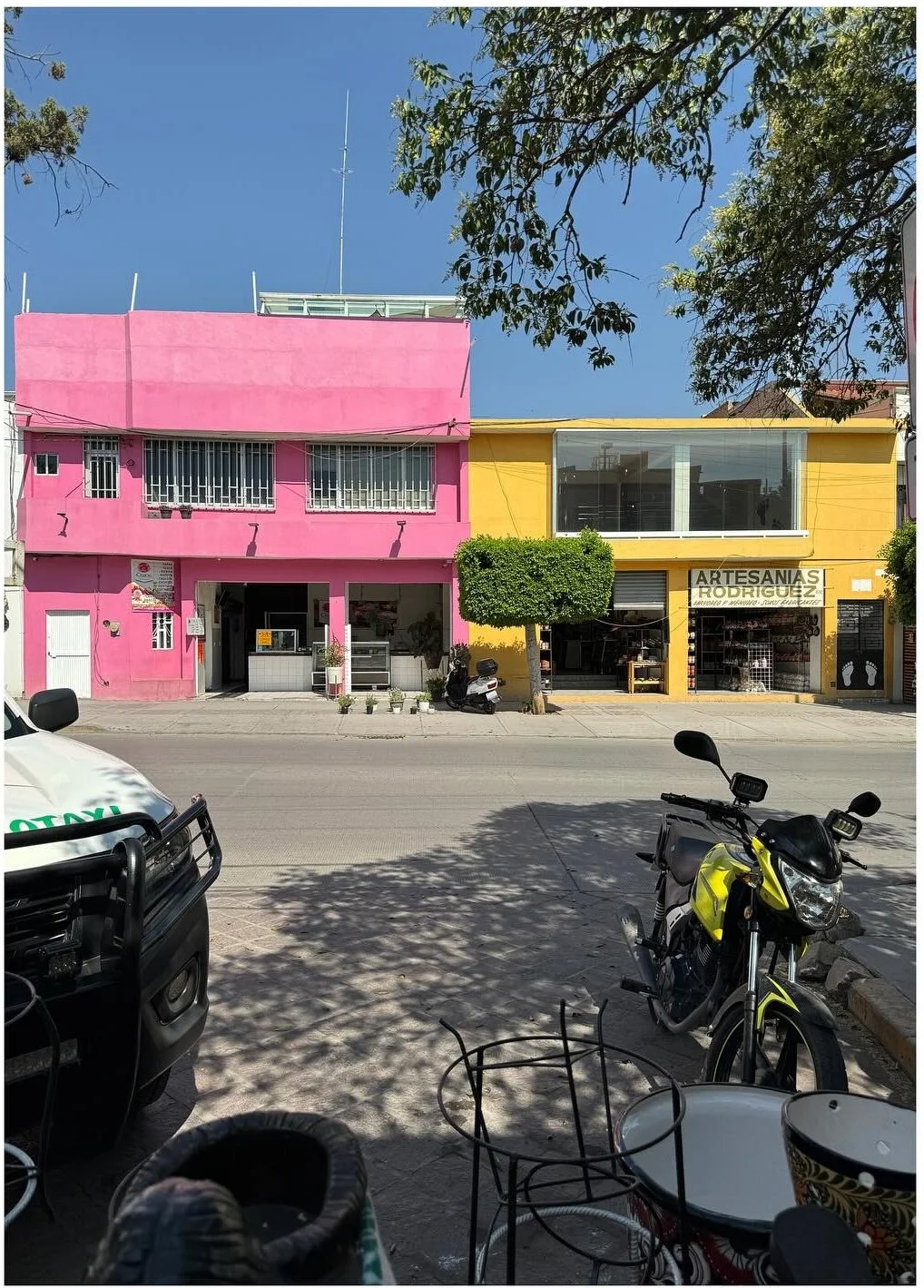 Pink yellow and green storefronts lining a sunny street
