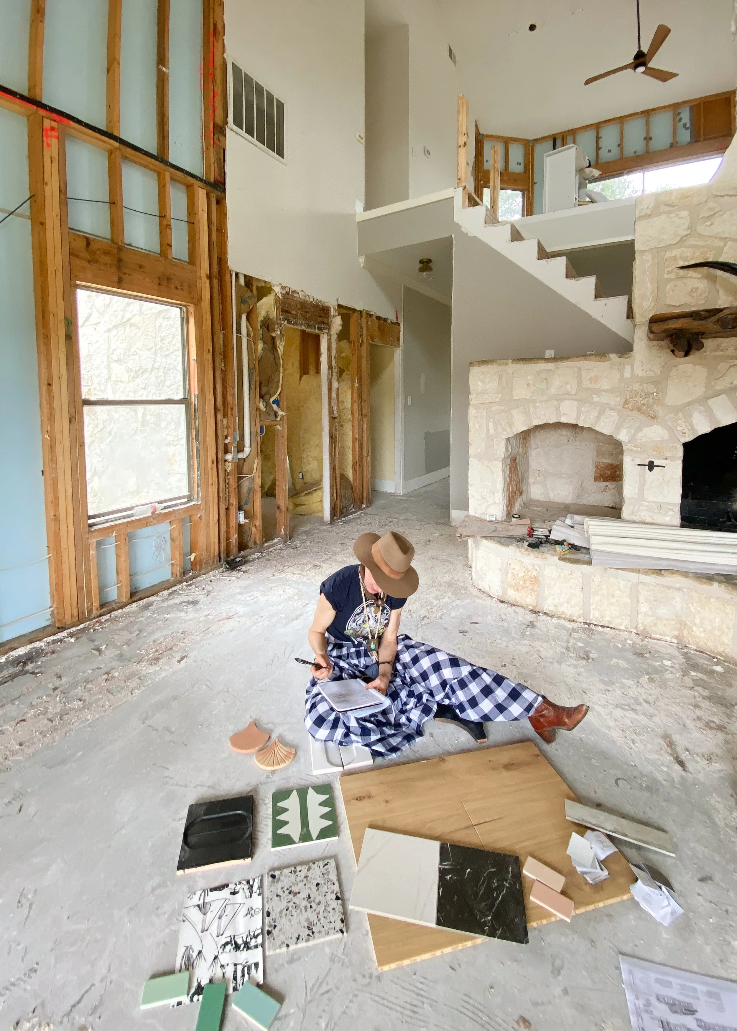 Amy Pigliacampo reviewing material samples beside a stone fireplace during renovation.