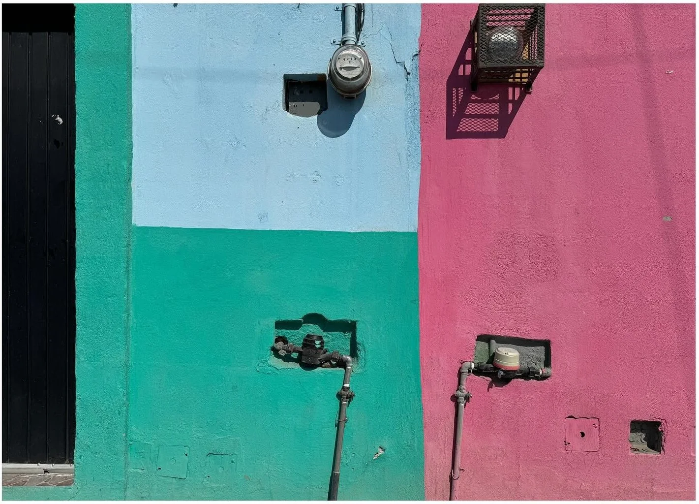 Turquoise green and pink stucco walls with small metal fixtures