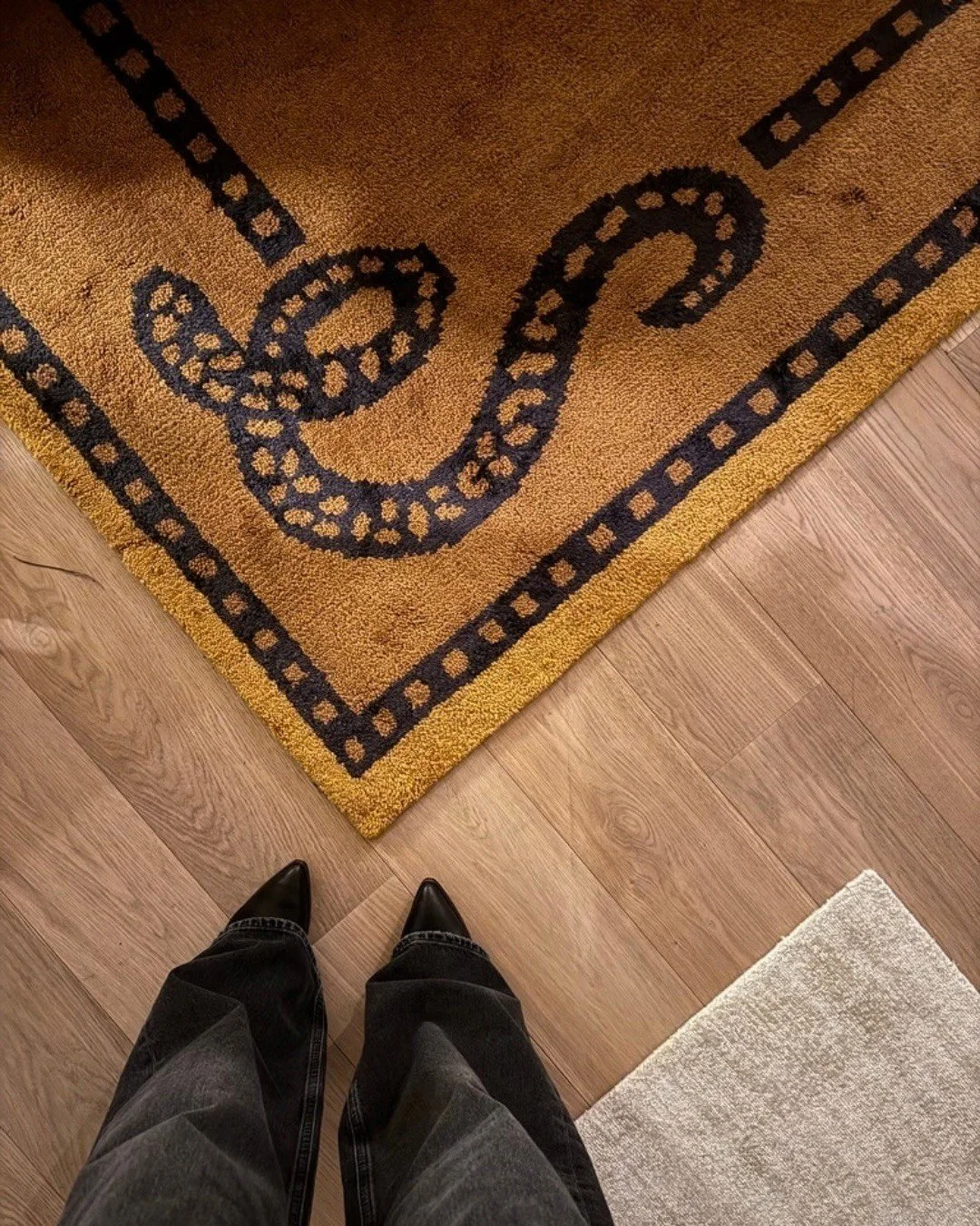 Patterned mustard doormat on a pale wood floor