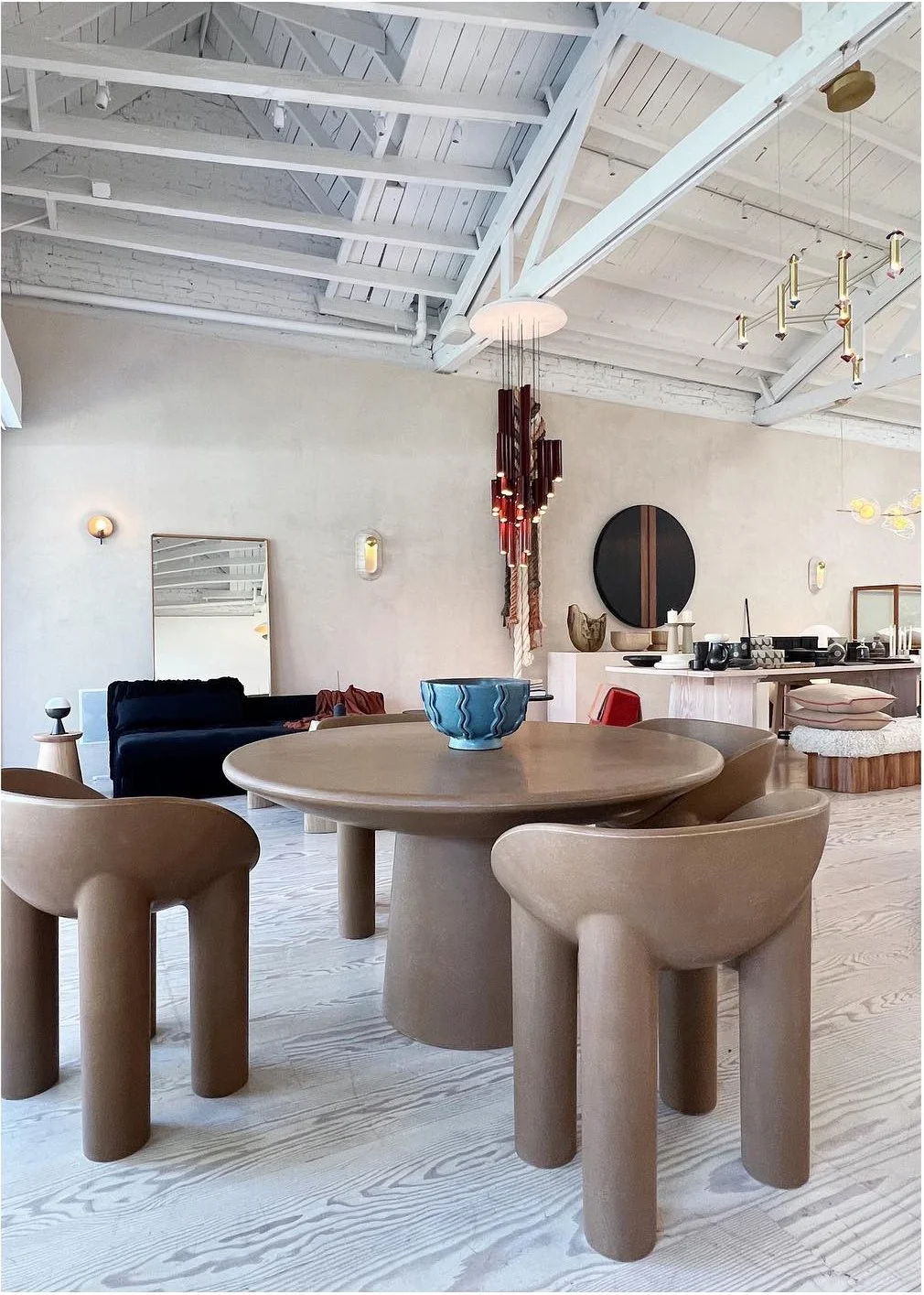 Sculptural pale chairs around a round table in a bright furniture showroom