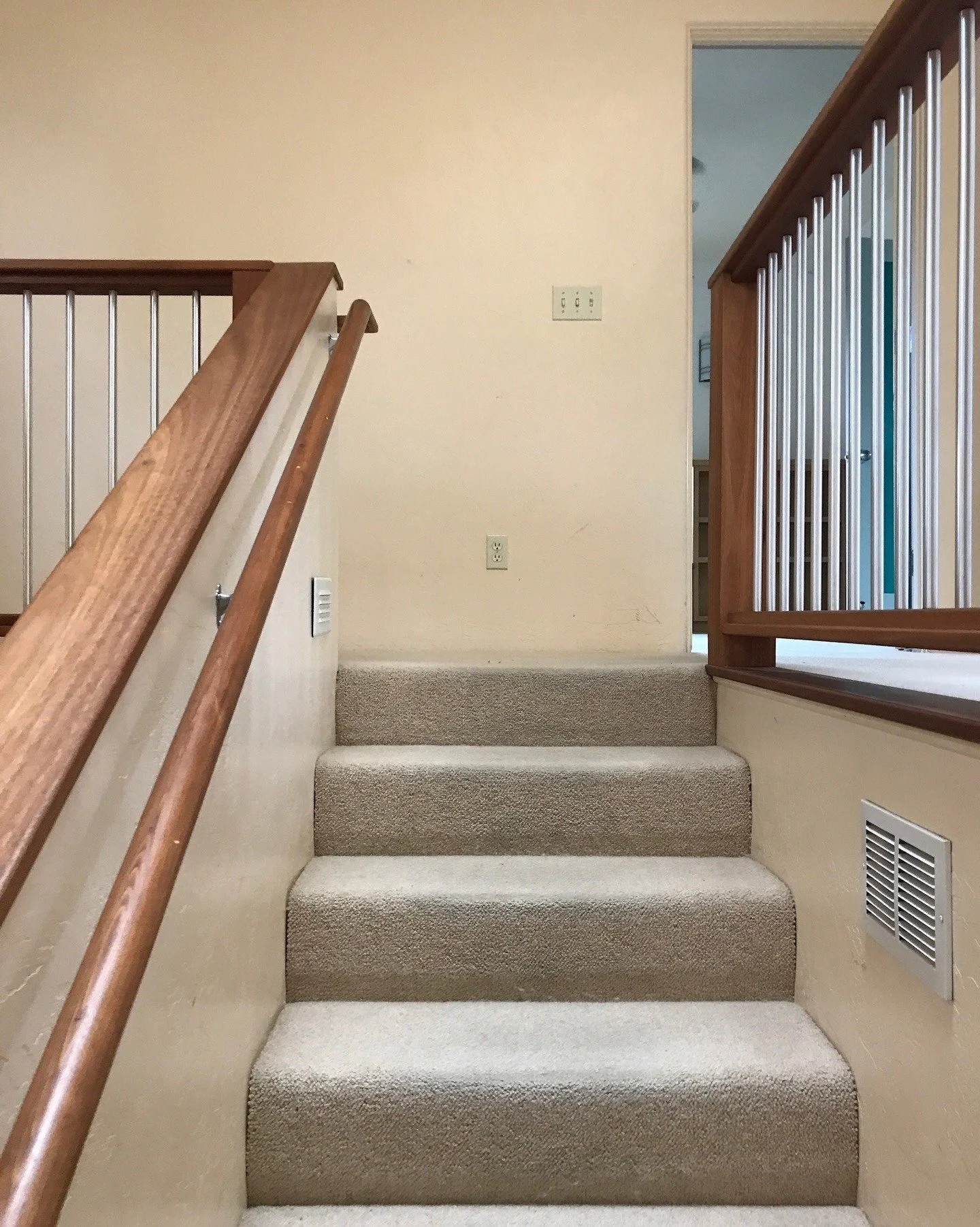 Carpeted stair landing with wood rails before renovation