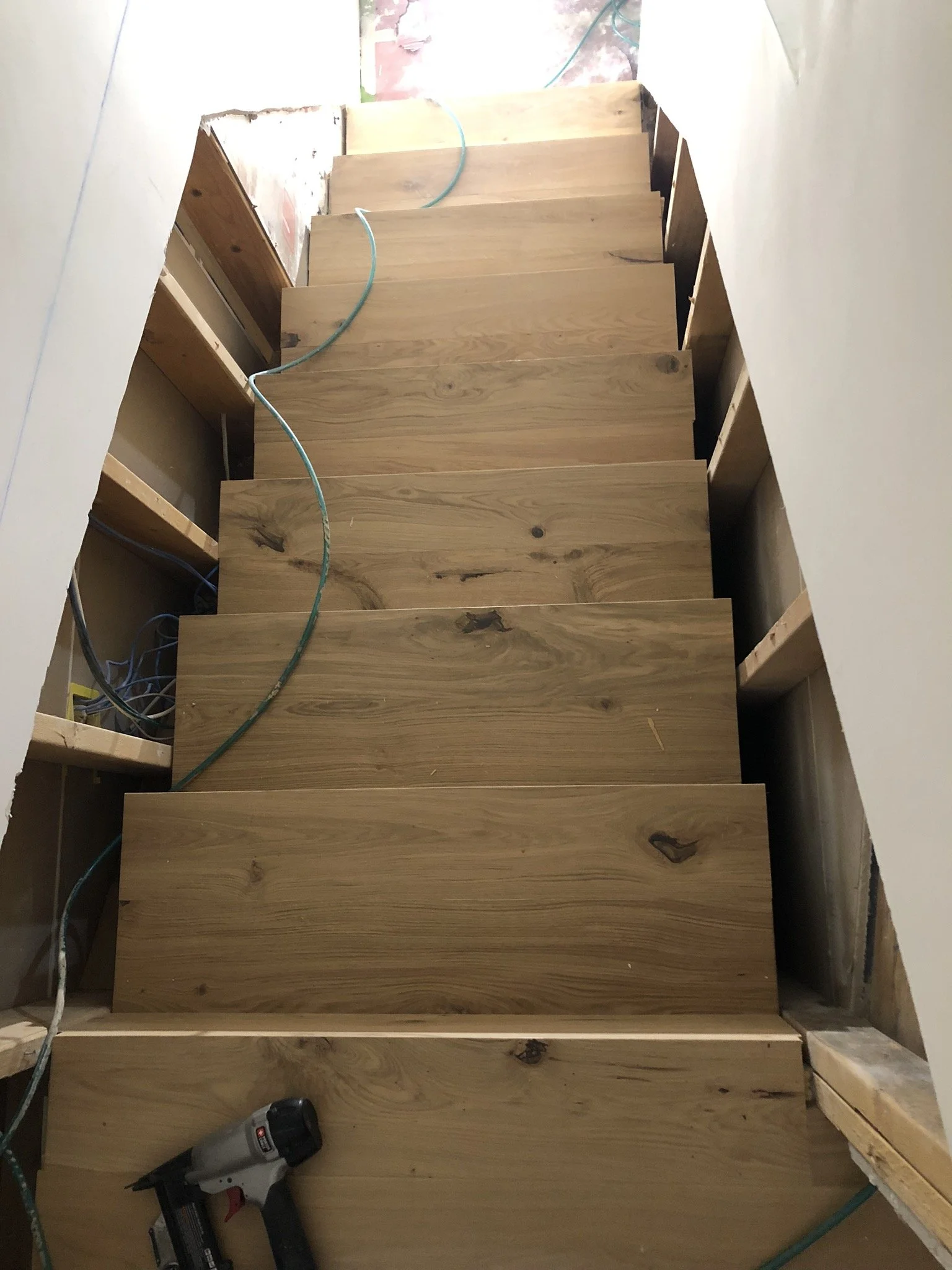 New wood stairs under construction with tools and electrical cords.