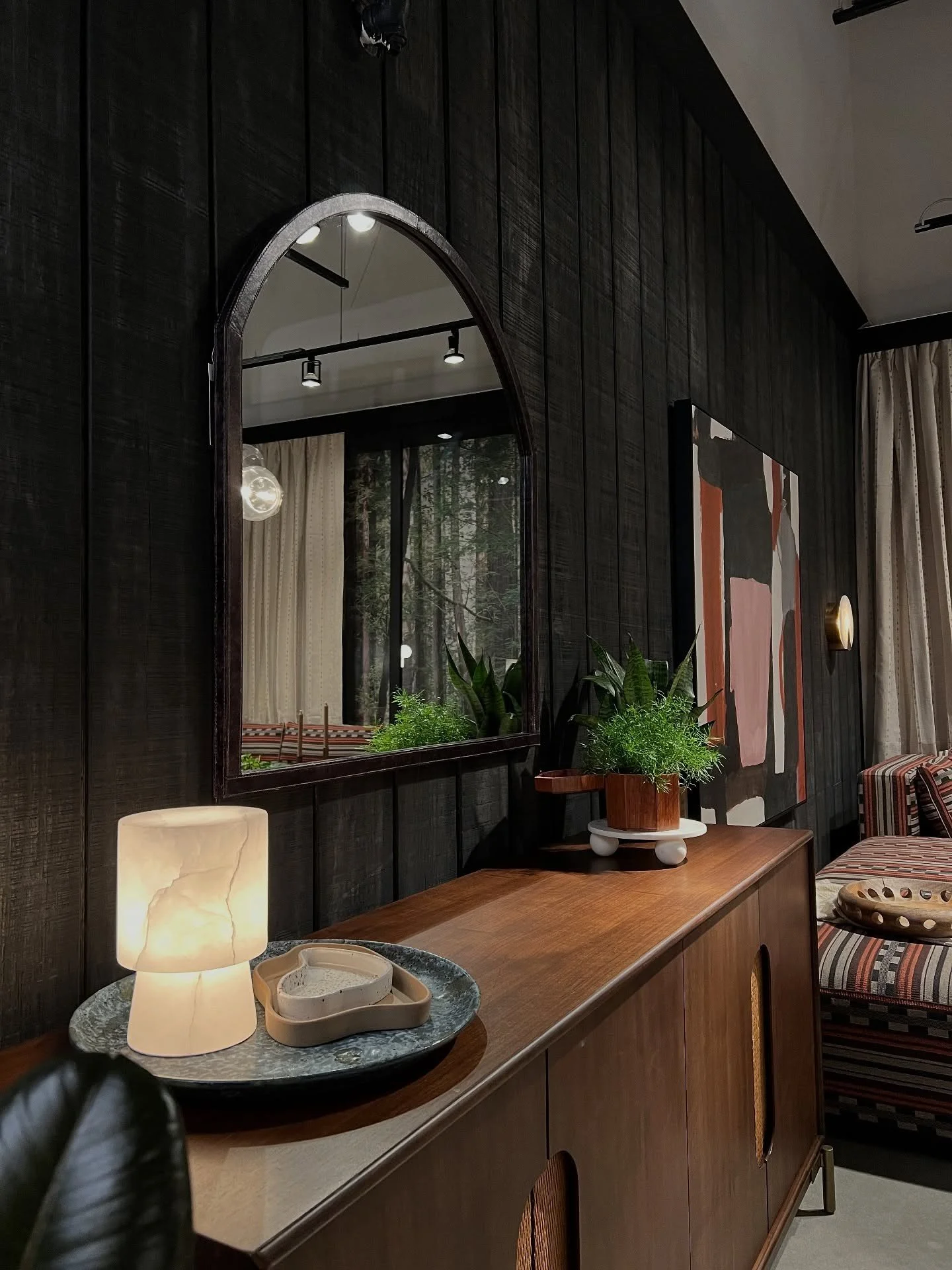 Wood console beneath an arched mirror on a dark wall