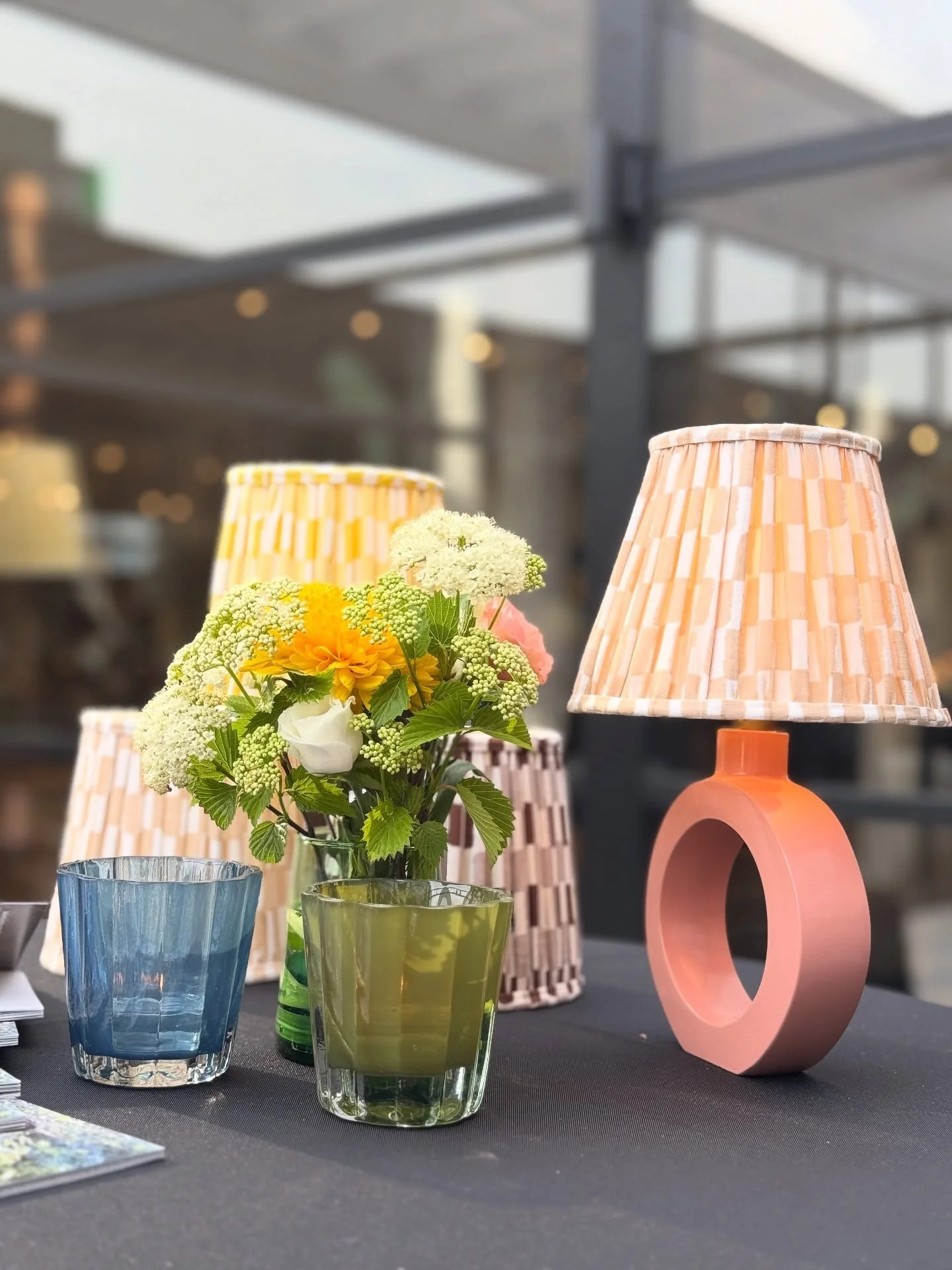 Pink sculptural table lamp beside flowers on a stone counter