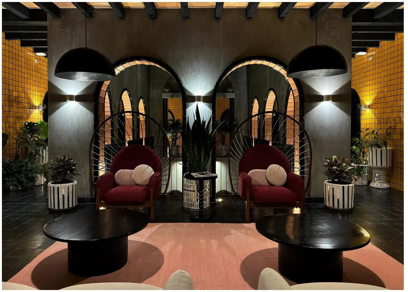 Symmetrical lounge seating beneath arched mirrors and yellow tile
