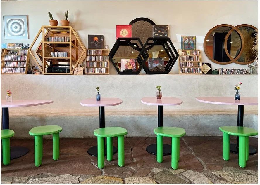 Bright green stools beneath a colorful bar and display of decorative objects