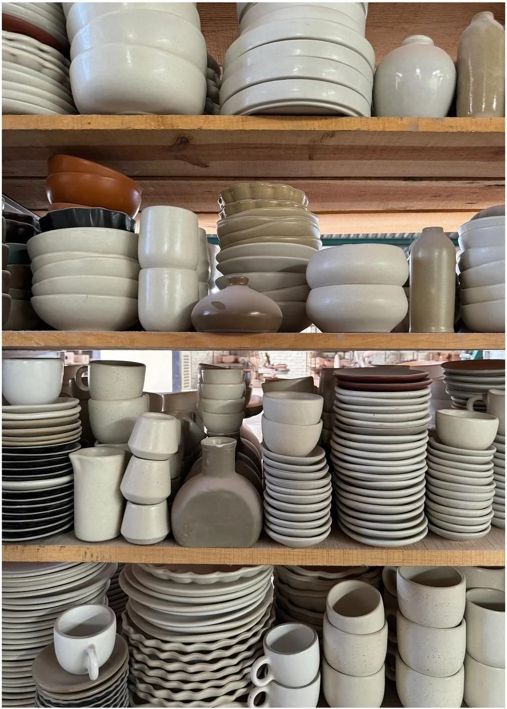 Shelves tightly stacked with white bowls plates mugs and dishes