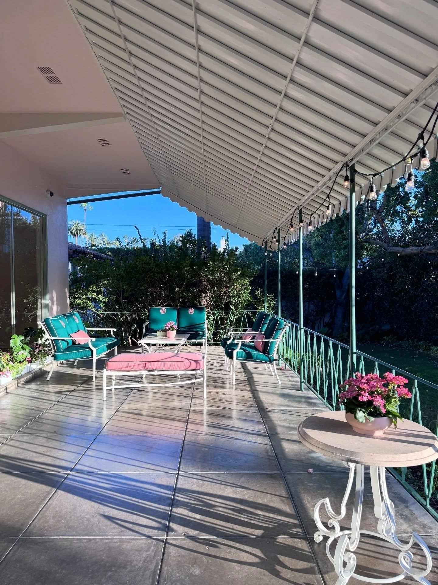 Covered veranda with metal chairs and green cushions