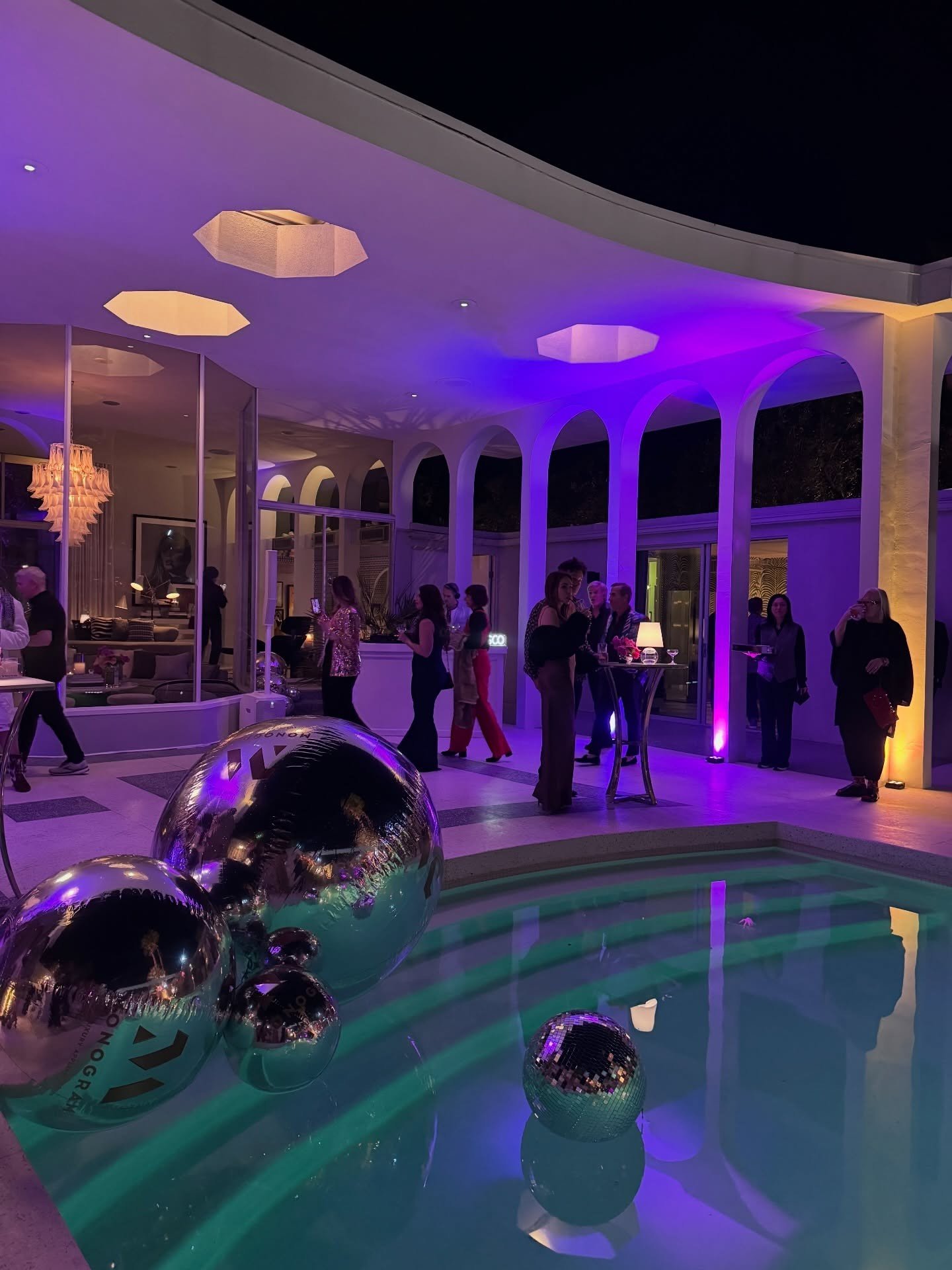 Poolside terrace with warm pendant lights and purple accent lighting