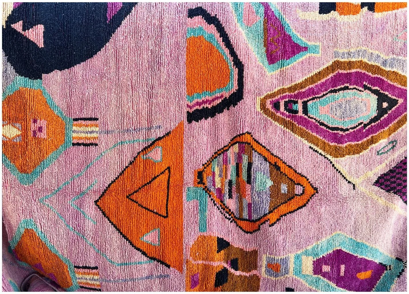 Colorful vintage rug with geometric motifs in pink orange blue and yellow