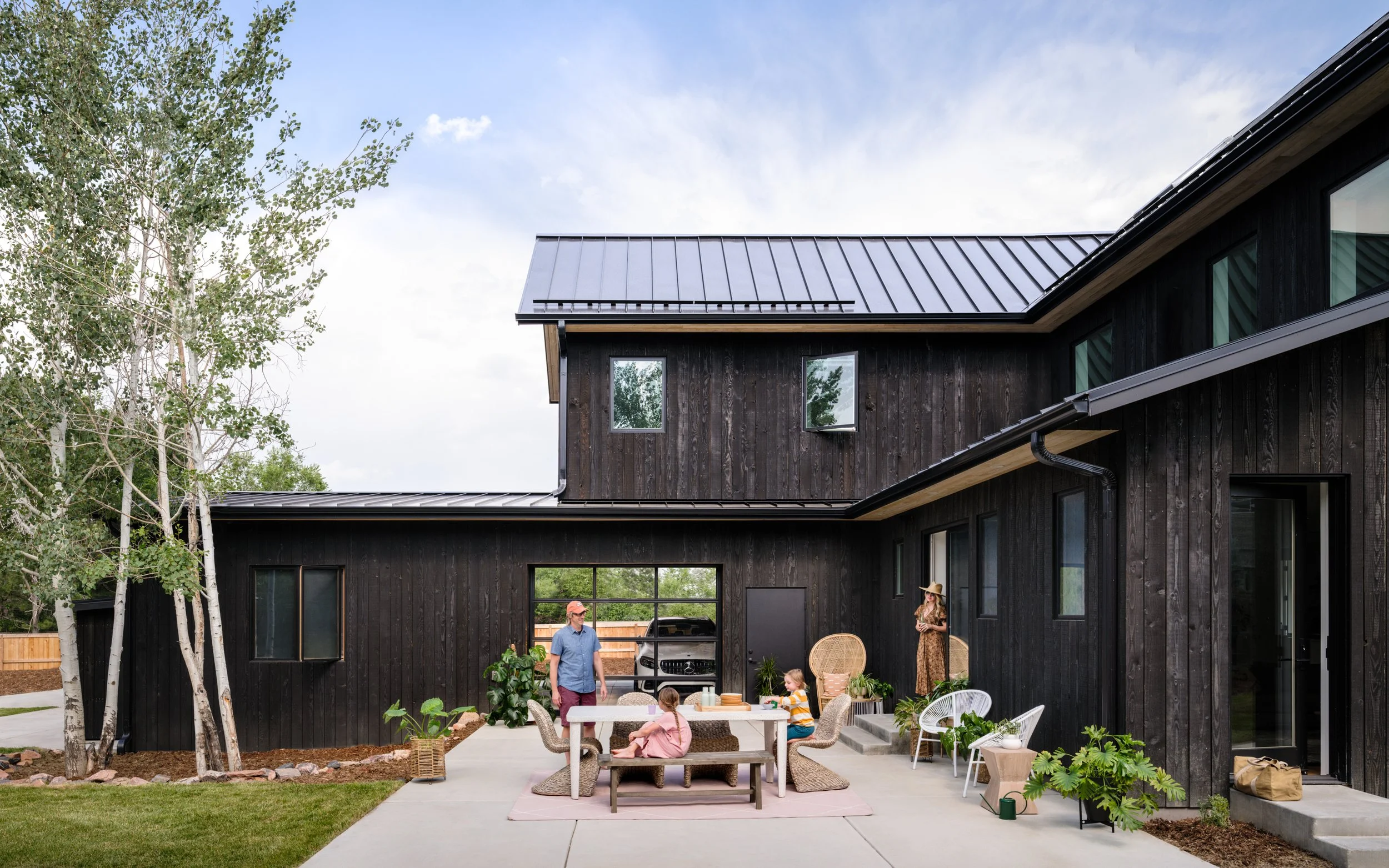 Patio outside a dark wood home, with a dining table and chairs.