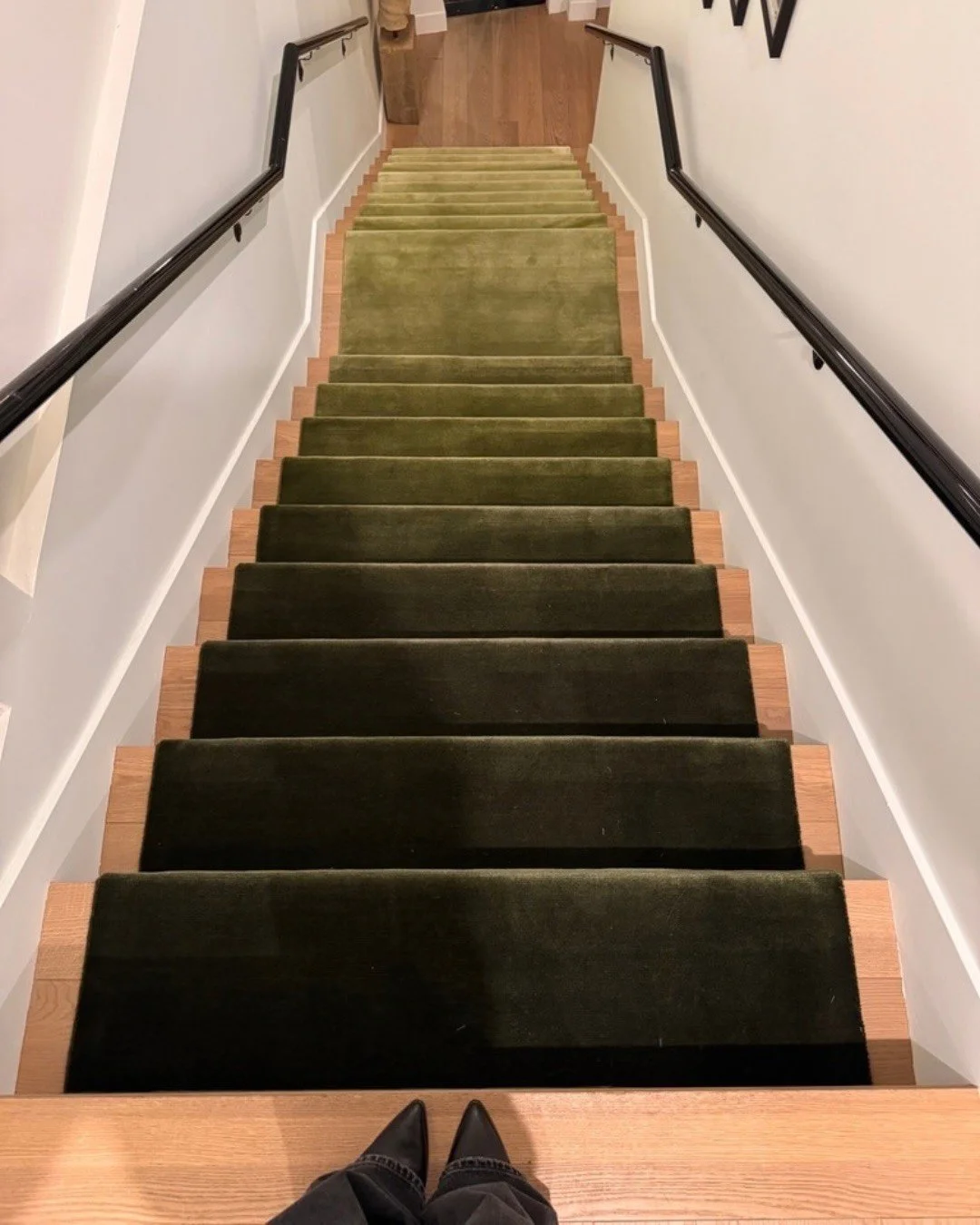 Green carpet runner on a staircase with black handrails