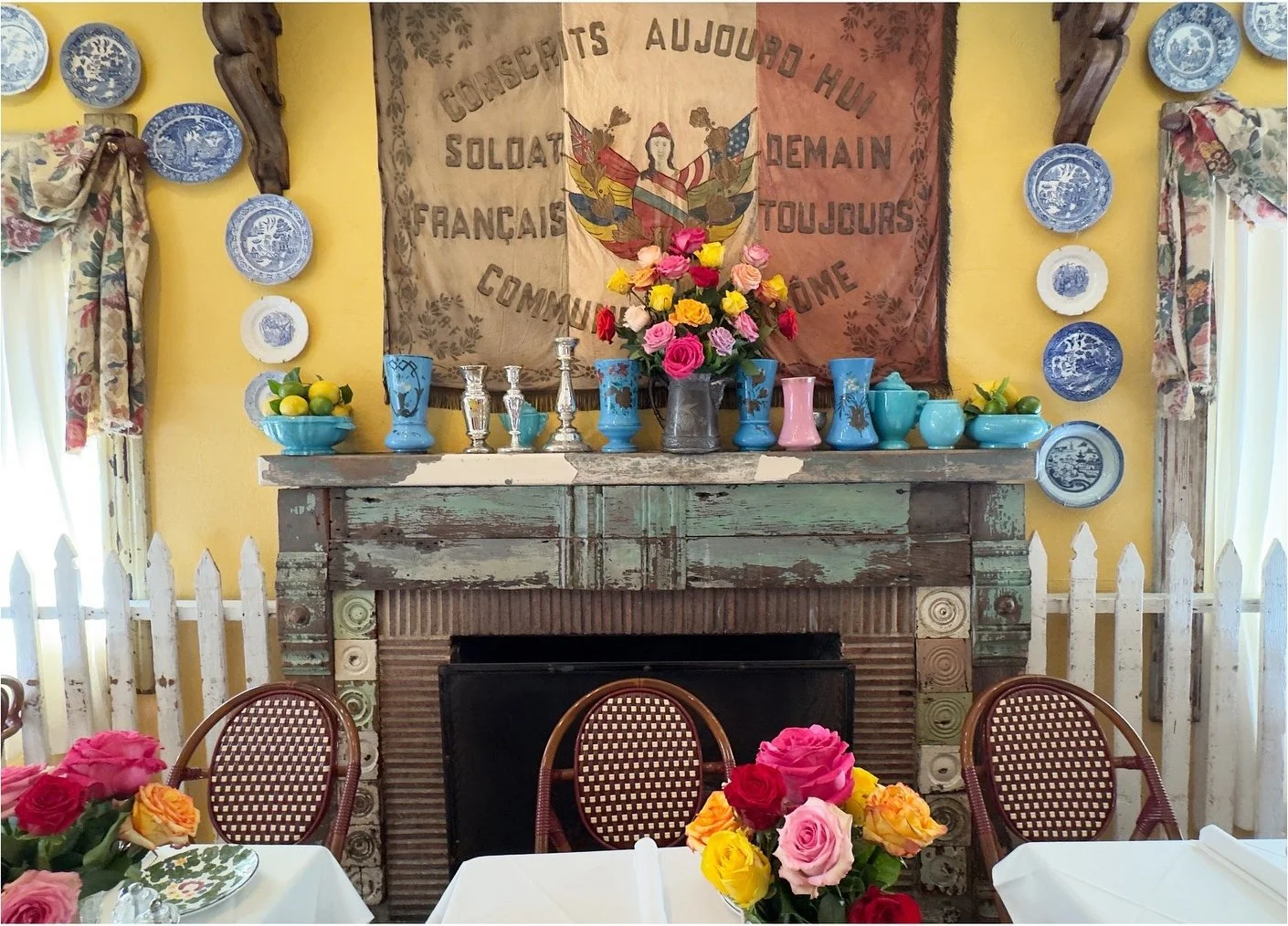 Restaurant fireplace surrounded by blue plates and bright flowers