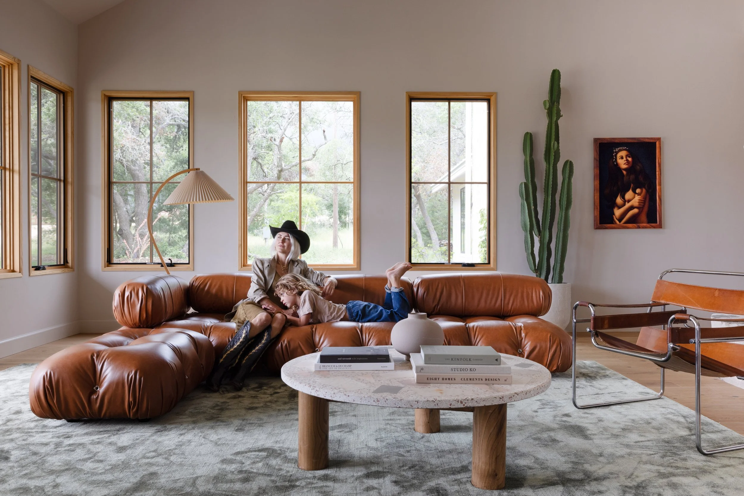 Living room with a rust-colored sofa, round coffee table, and tall windows.