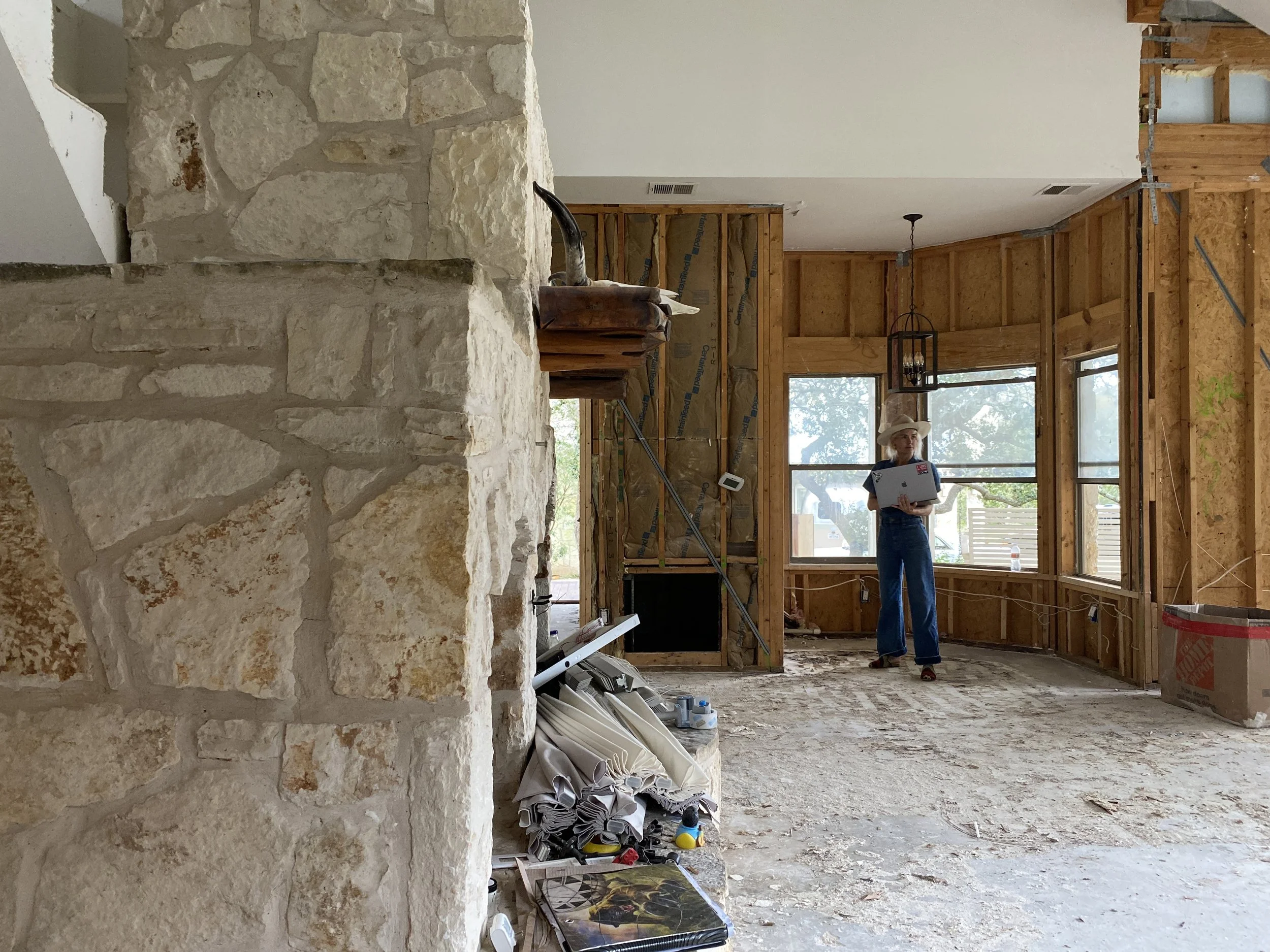 Worker in a room under renovation with exposed framing and a stone fireplace.
