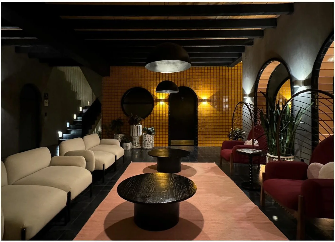 Pale sofa and dark coffee tables beside yellow tiled arches