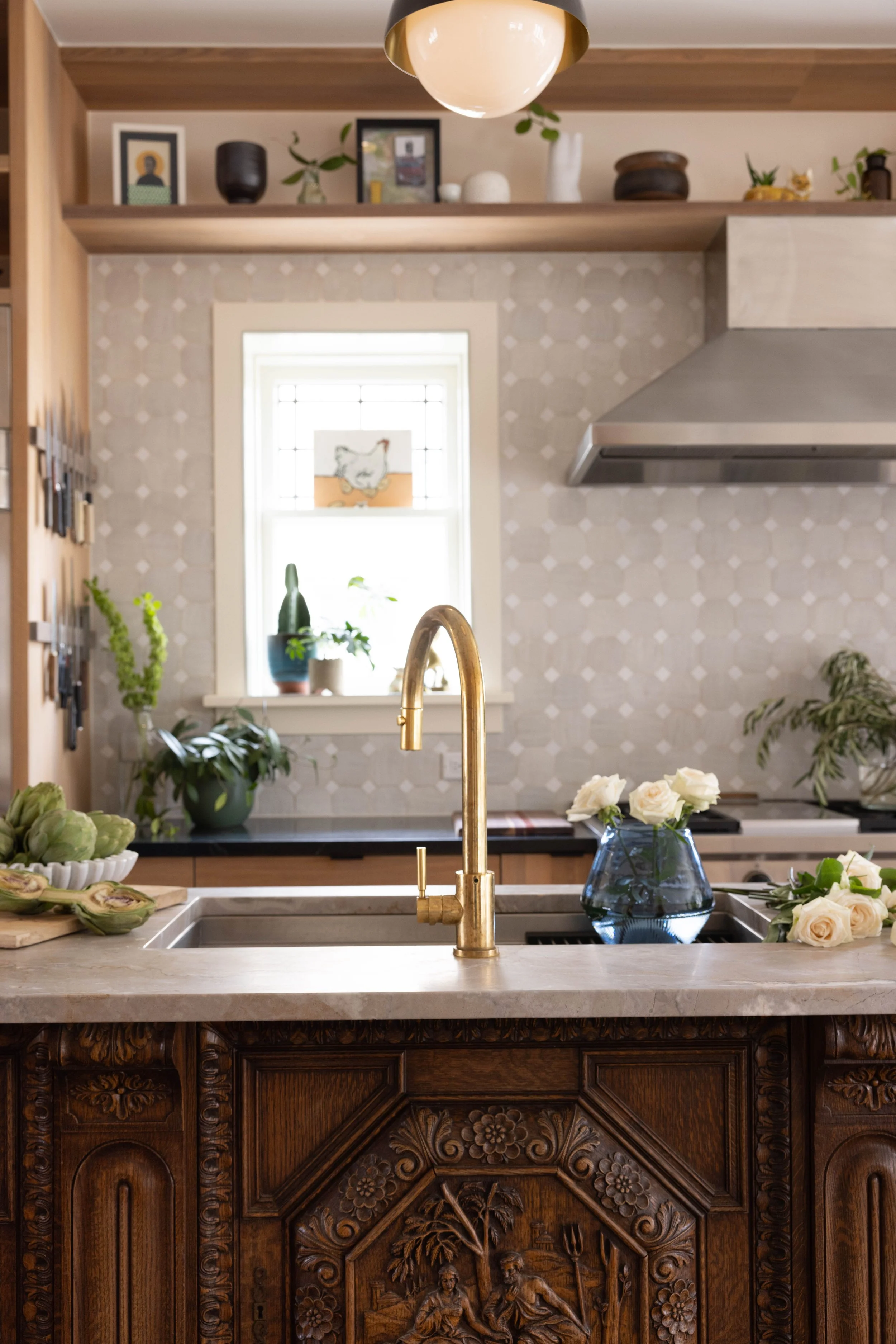 Kitchen with carved wood cabinetry, a brass faucet, and open shelves.