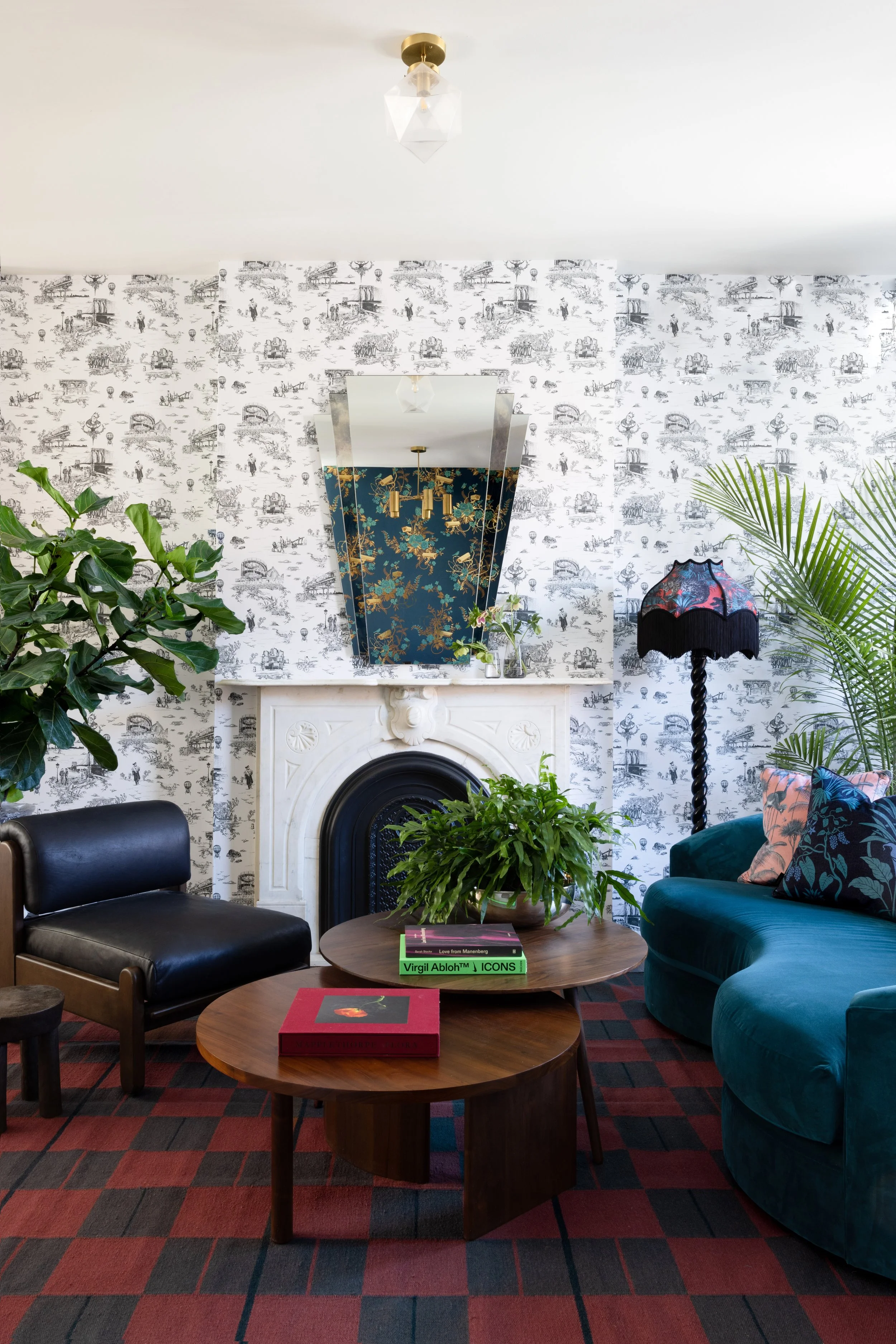 Living room with illustrated wallpaper, a fireplace, teal sofa, and patterned rug.