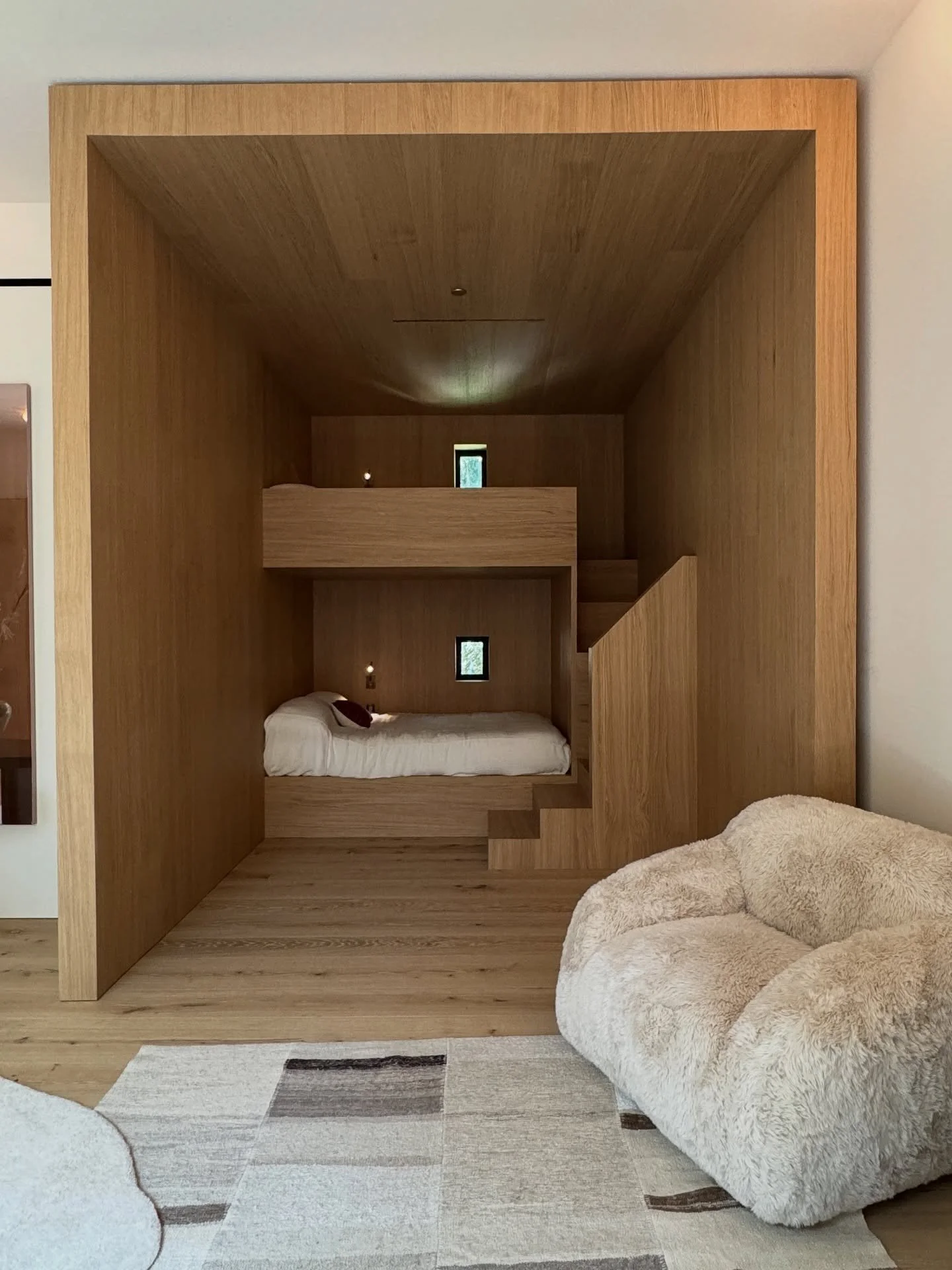 Recessed wood-paneled sleeping alcove beside a curved pale sofa