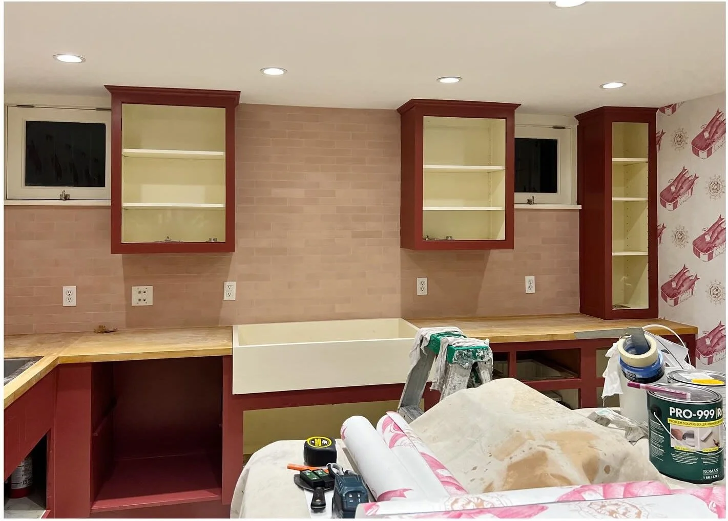 Laundry room during installation with burgundy cupboards and tiled walls
