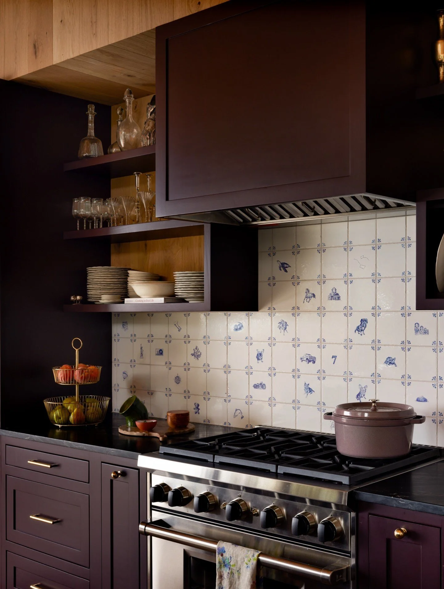 Dark plum kitchen cabinetry with a black range and tiled backsplash