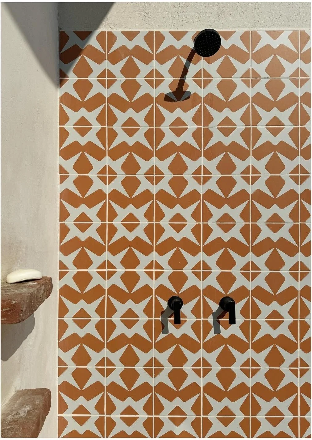 Outdoor shower with terracotta geometric patterned tile and black fixtures