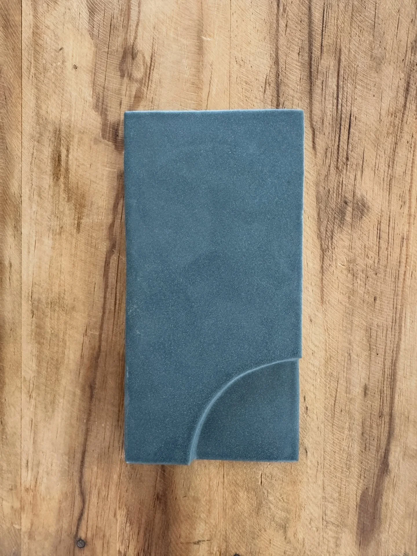 Blue rectangular tile sample with a curved raised detail