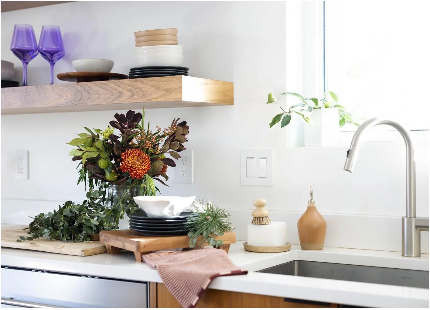 Kitchen sink and counter styled with flowers dishes and colorful glasses