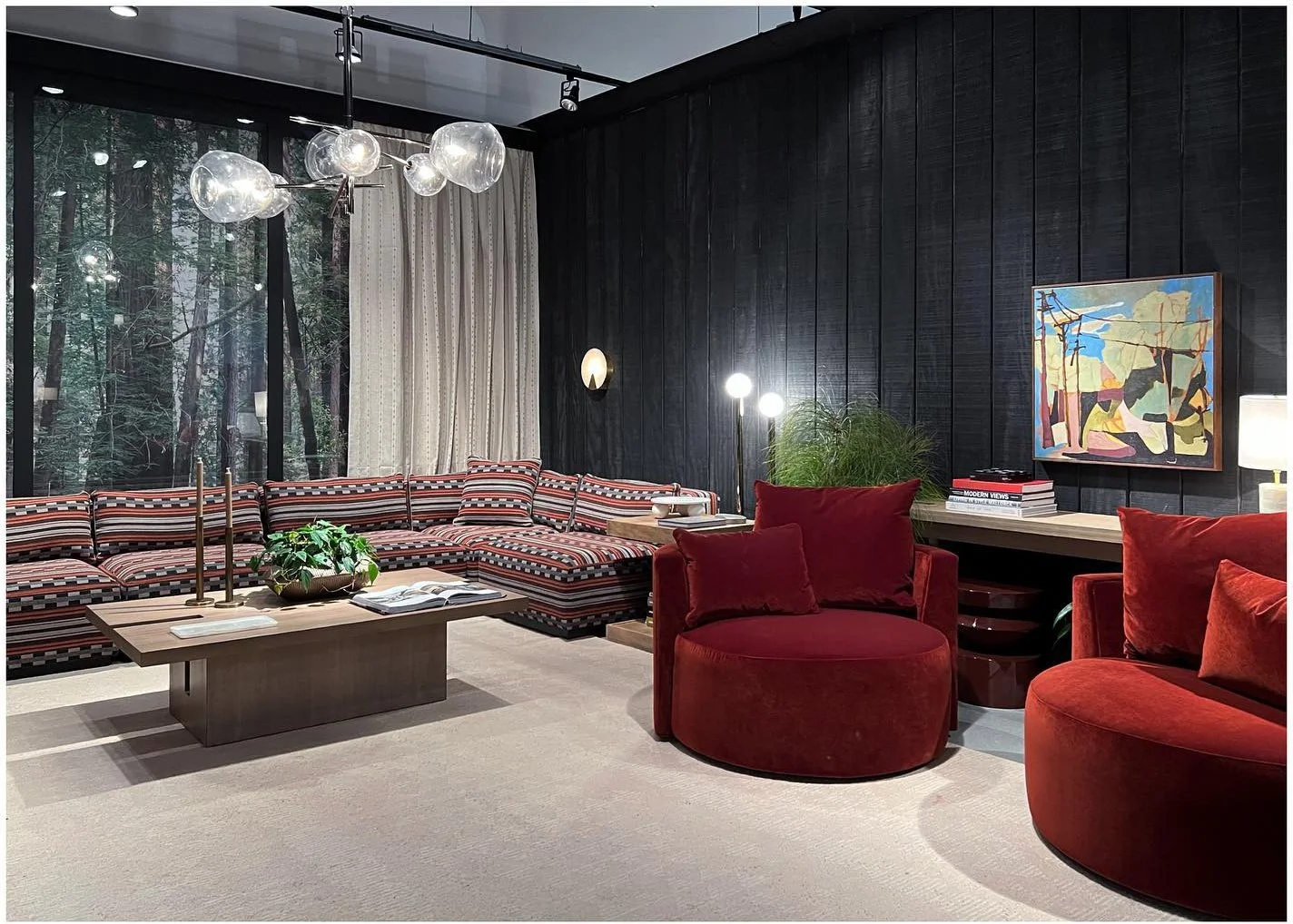 Red sculptural lounge chairs beside a large patterned sectional