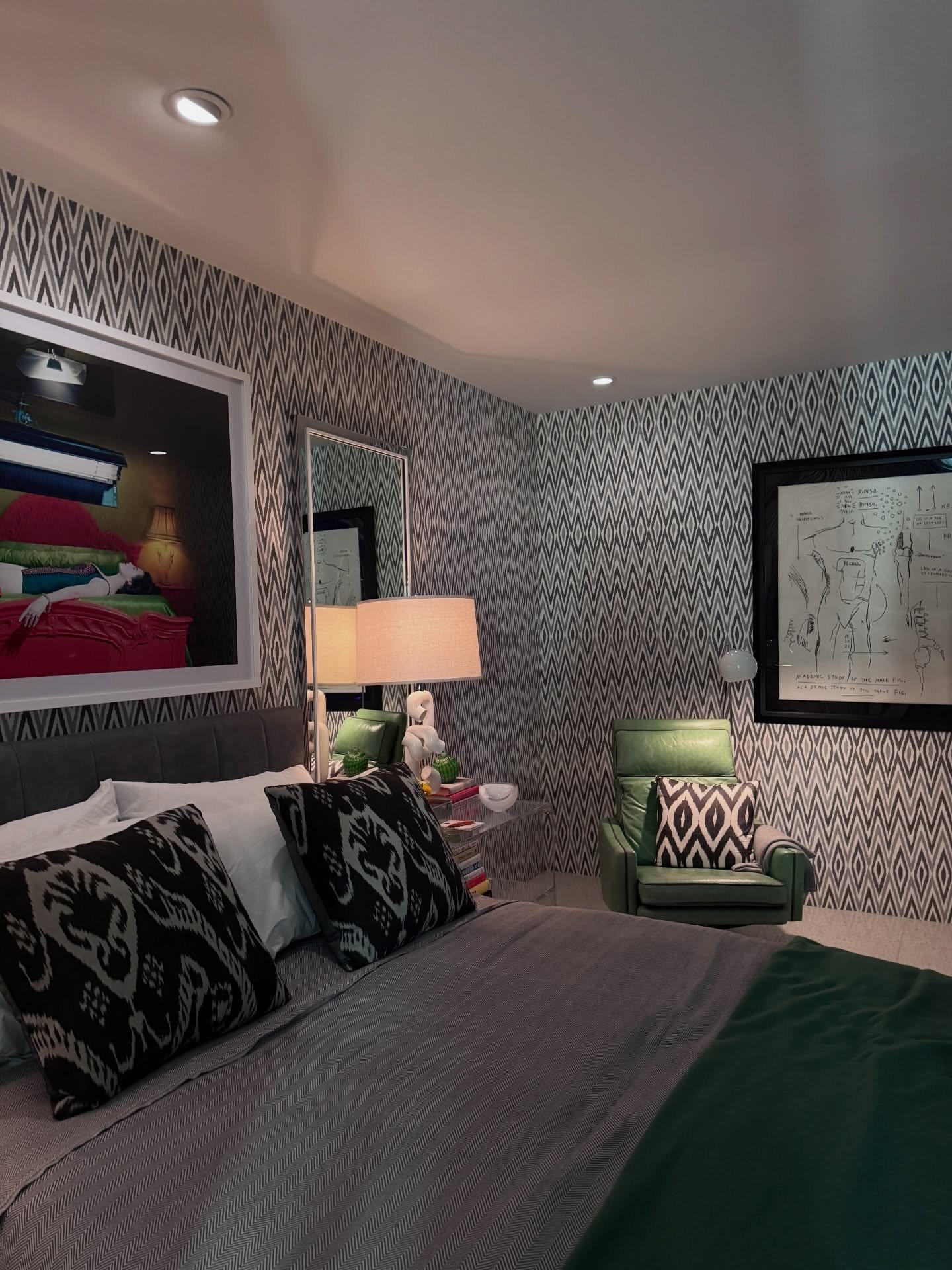 Bedroom with patterned wallpaper and layered monochrome bedding