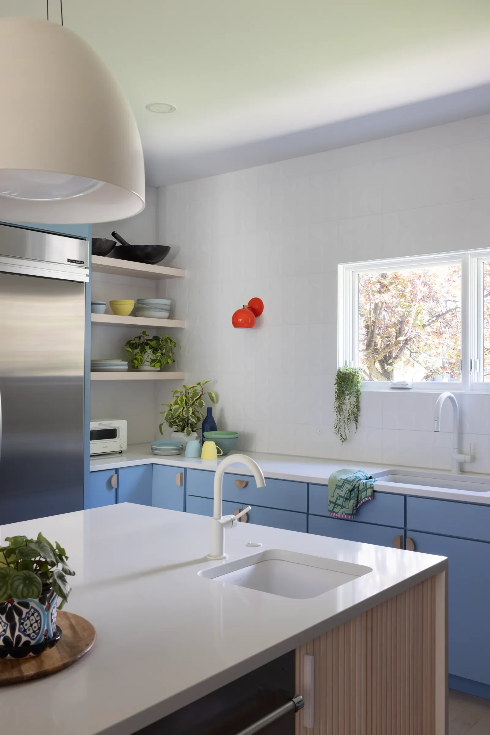 Kitchen with blue cabinets, white island, and a window over the sink.