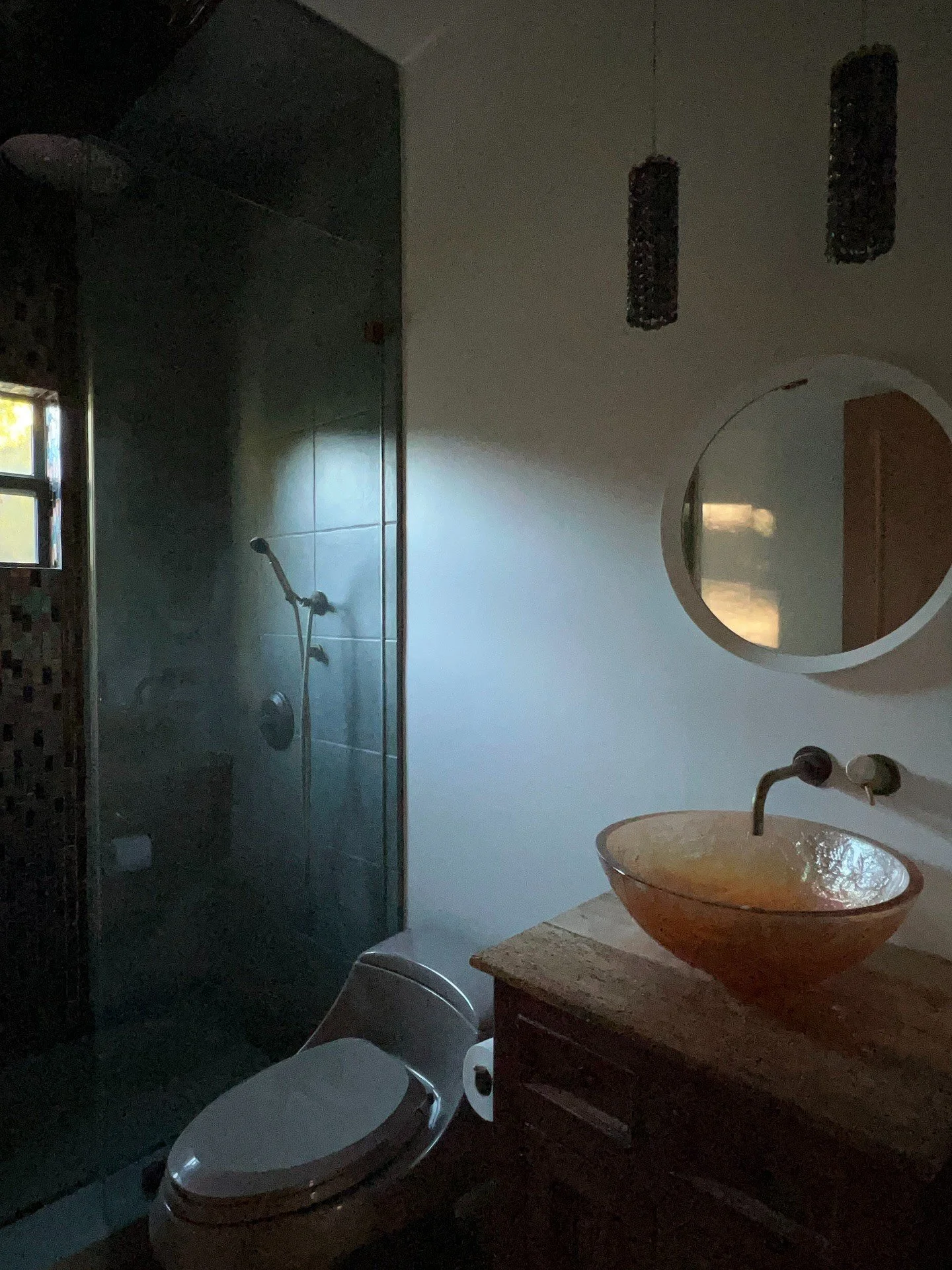 Original bathroom with amber vessel sink and dark stone shower