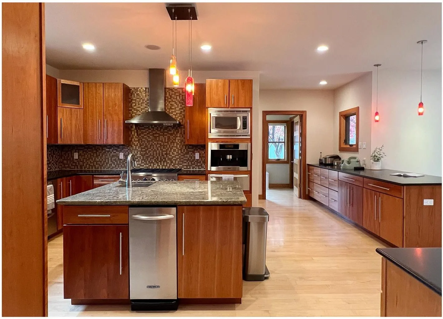 Original kitchen island surrounded by warm wood cabinets and stone counters
