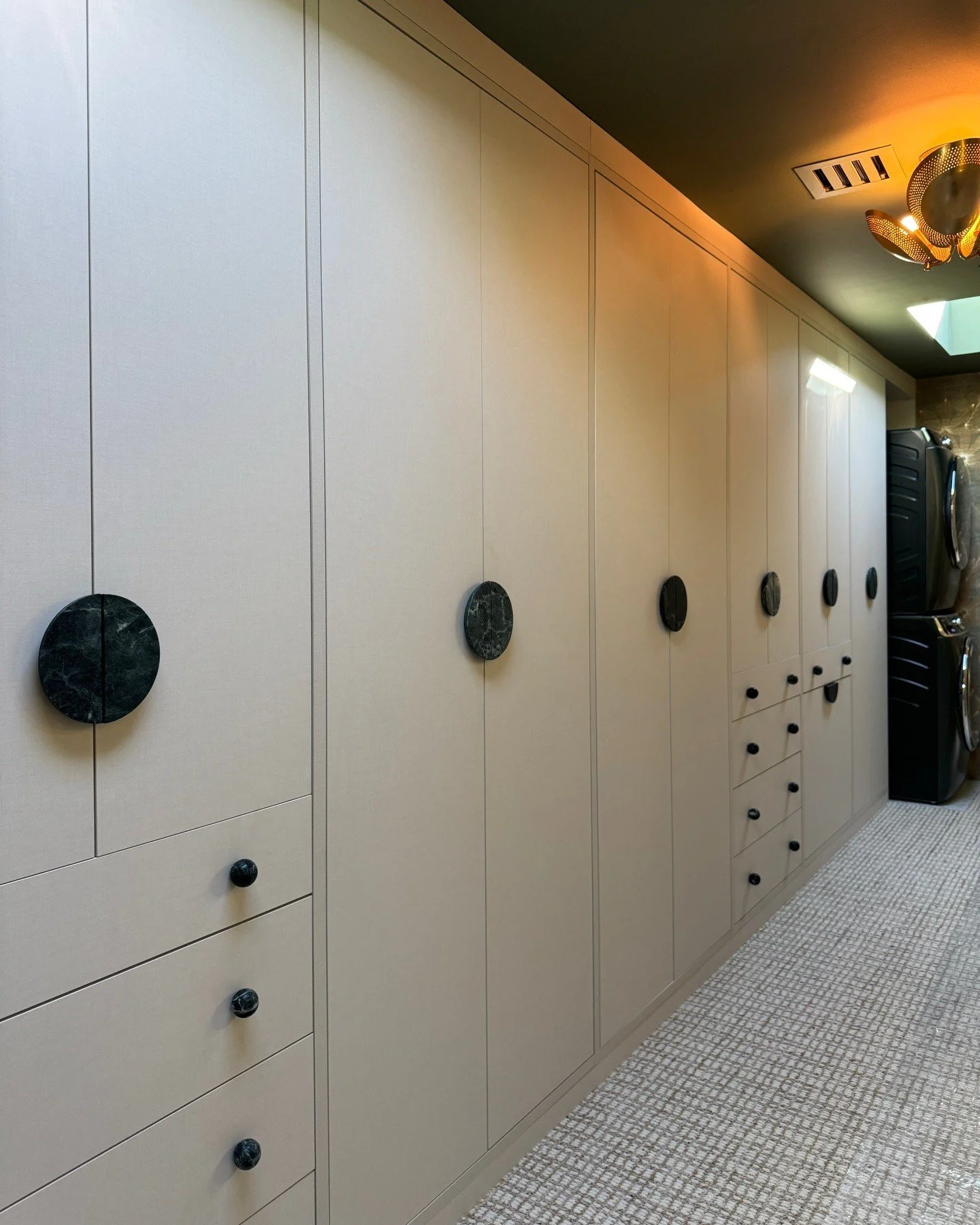 Wall of pale built-in cupboards with large circular pulls