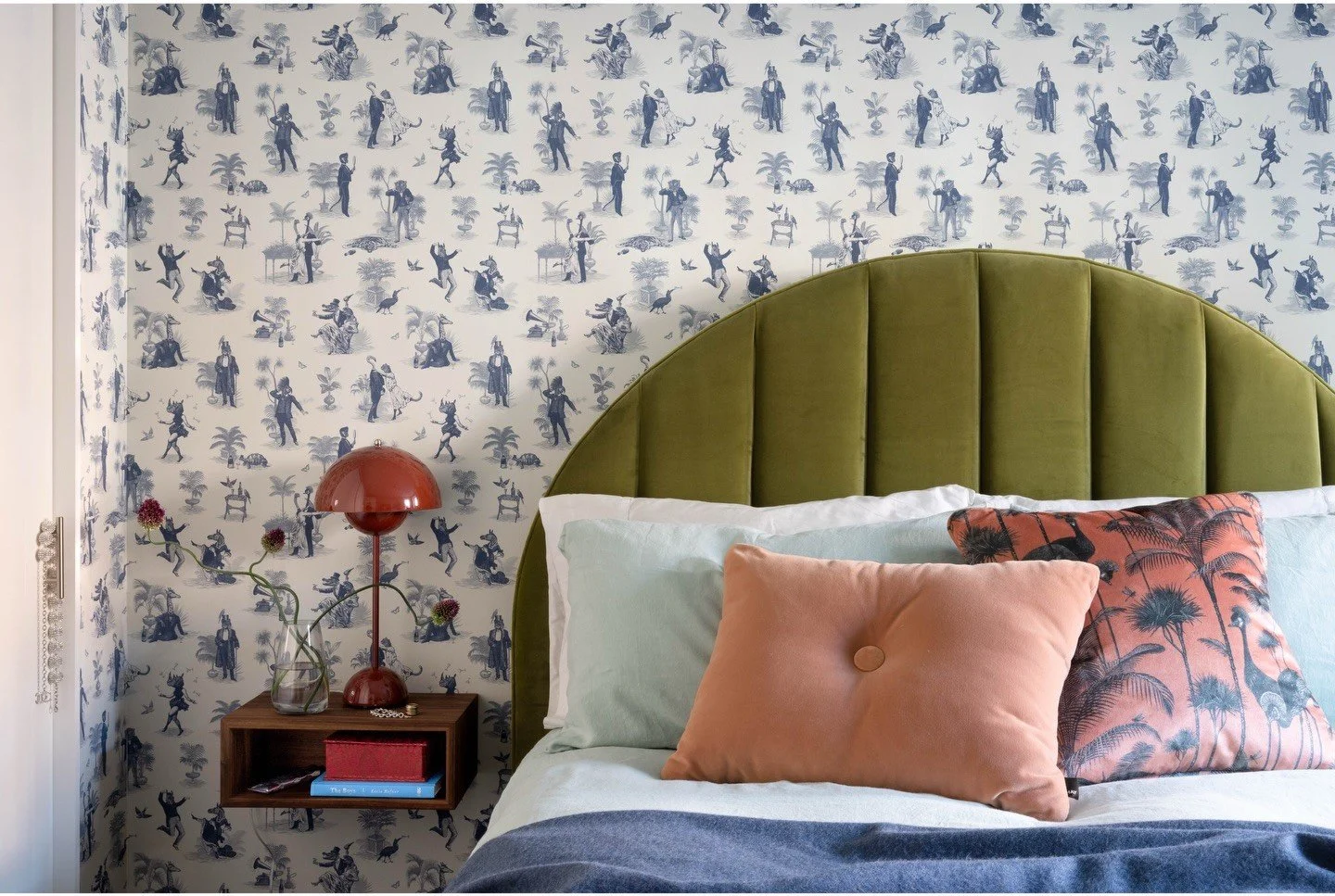 Green velvet headboard against delicate botanical wallpaper