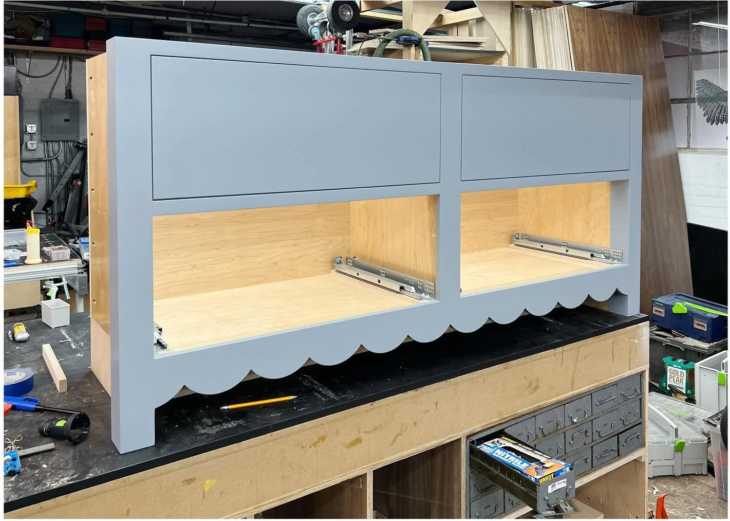 Blue-gray scalloped vanity cabinet under construction on a workshop bench