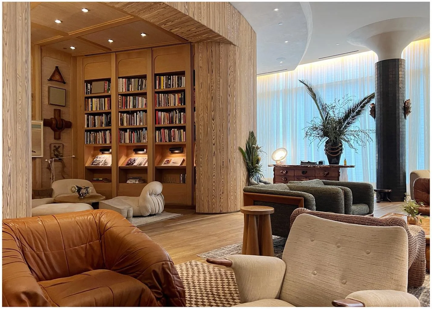 Warm hotel lounge with wood shelving curved seats and a marble table