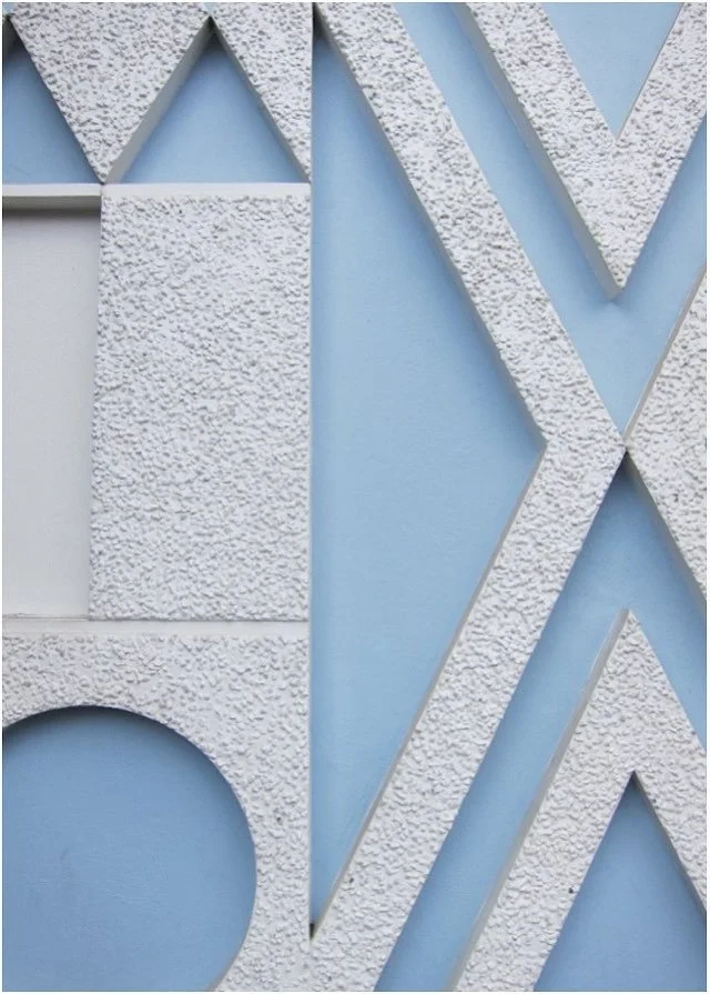 Raised geometric architectural shapes against a pale blue wall