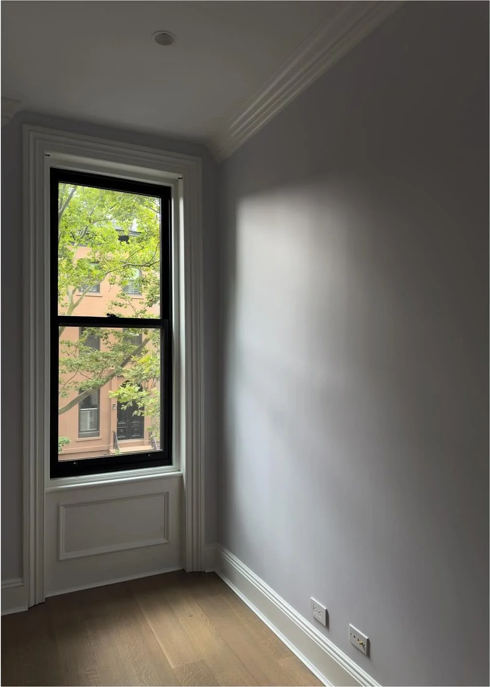 Tall narrow window and original trim in an empty brownstone room