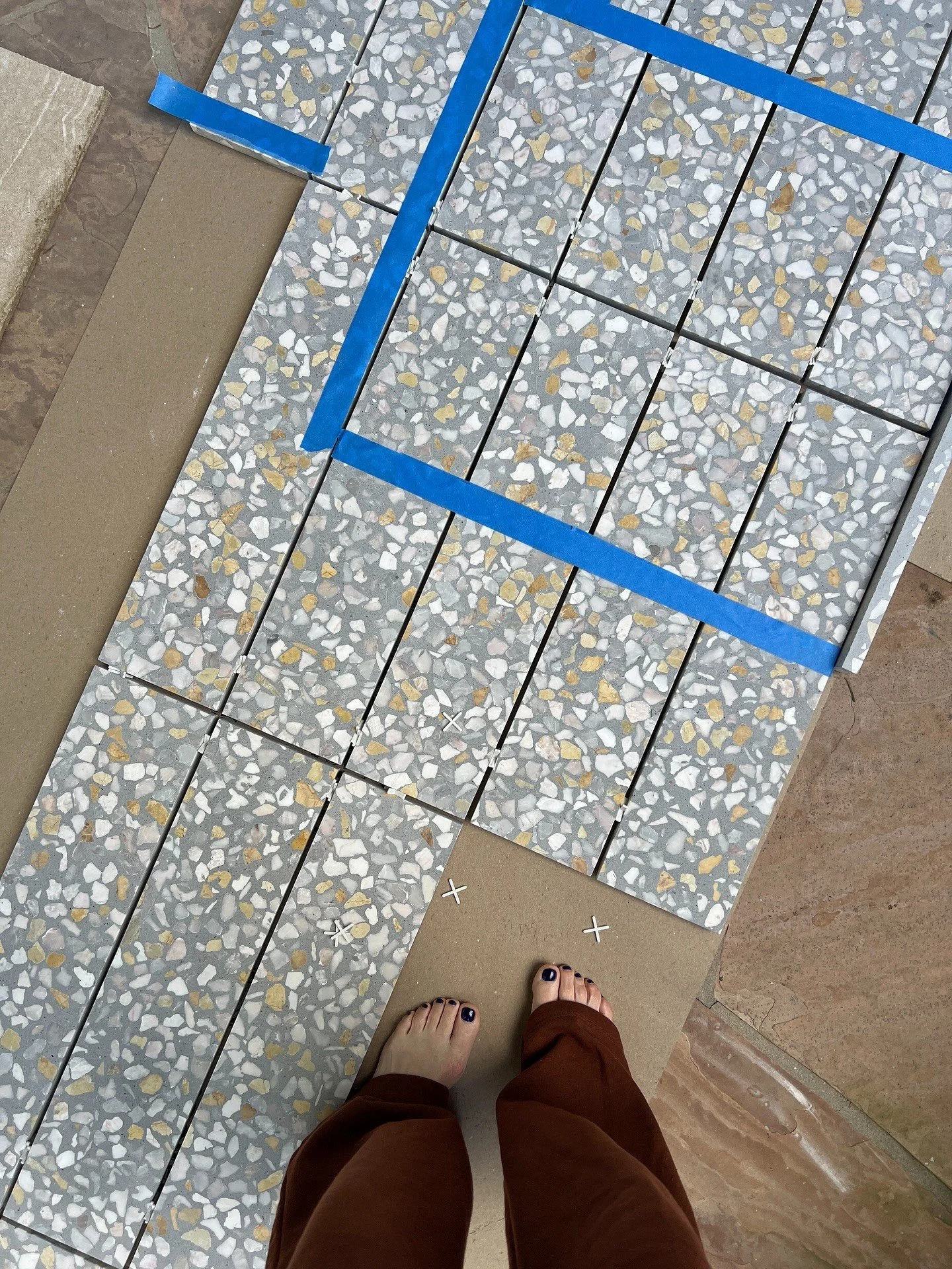 Terrazzo tile layout marked with blue tape on the floor