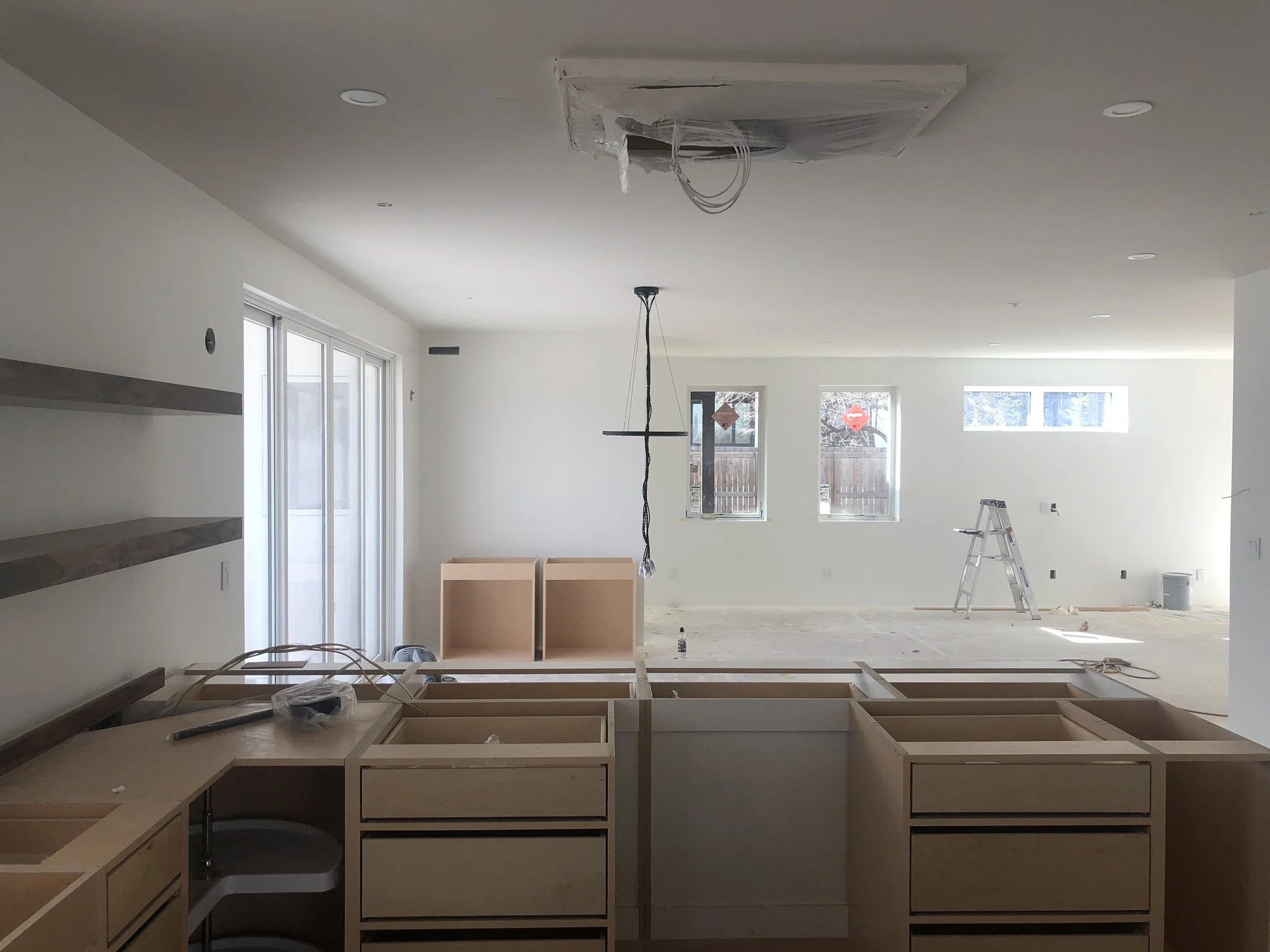 Kitchen under construction with unfinished cabinetry and exposed fittings.