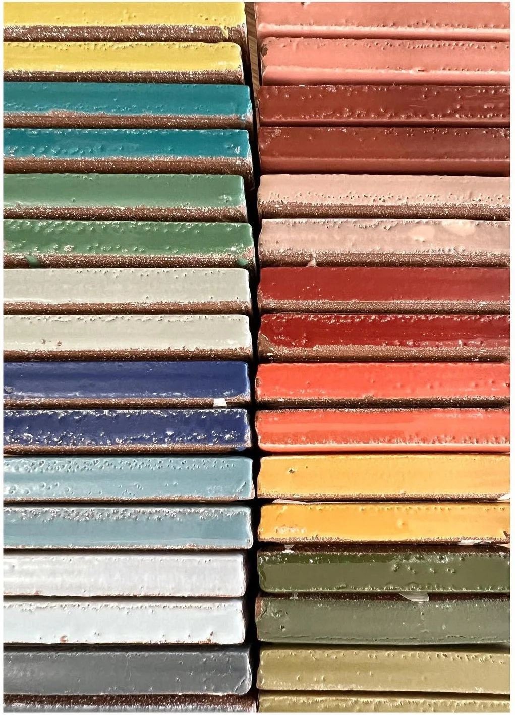 Glazed tile samples stacked in two rows of varied bright and muted colors