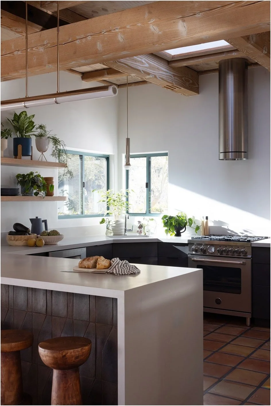 Gray kitchen cabinetry beside open shelves and a black counter