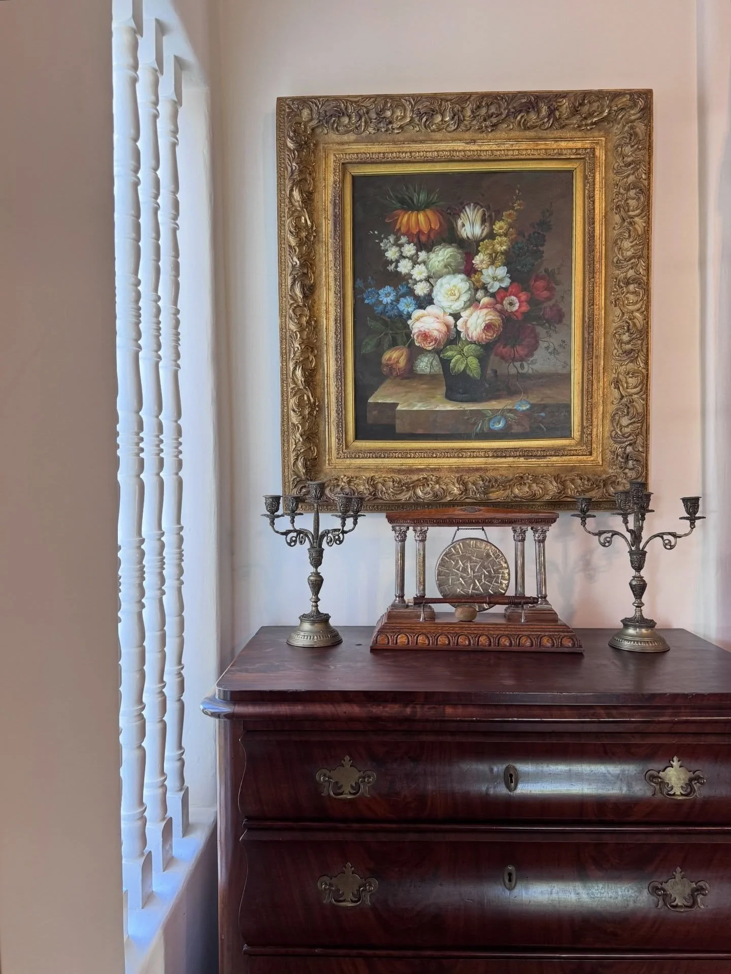 Antique wood chest beneath a framed floral still-life painting