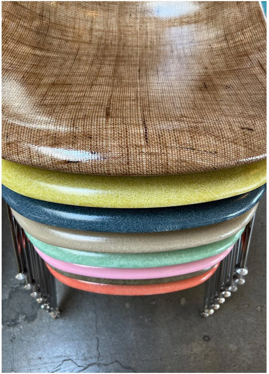 Stacked fiberglass chair shells in muted pink green and yellow