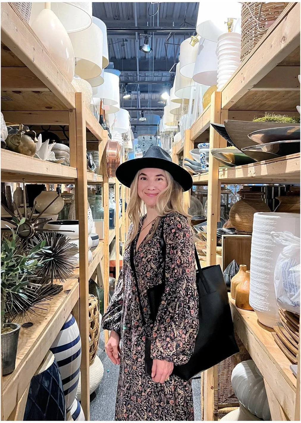 Amy standing between tall shelving units filled with styling props
