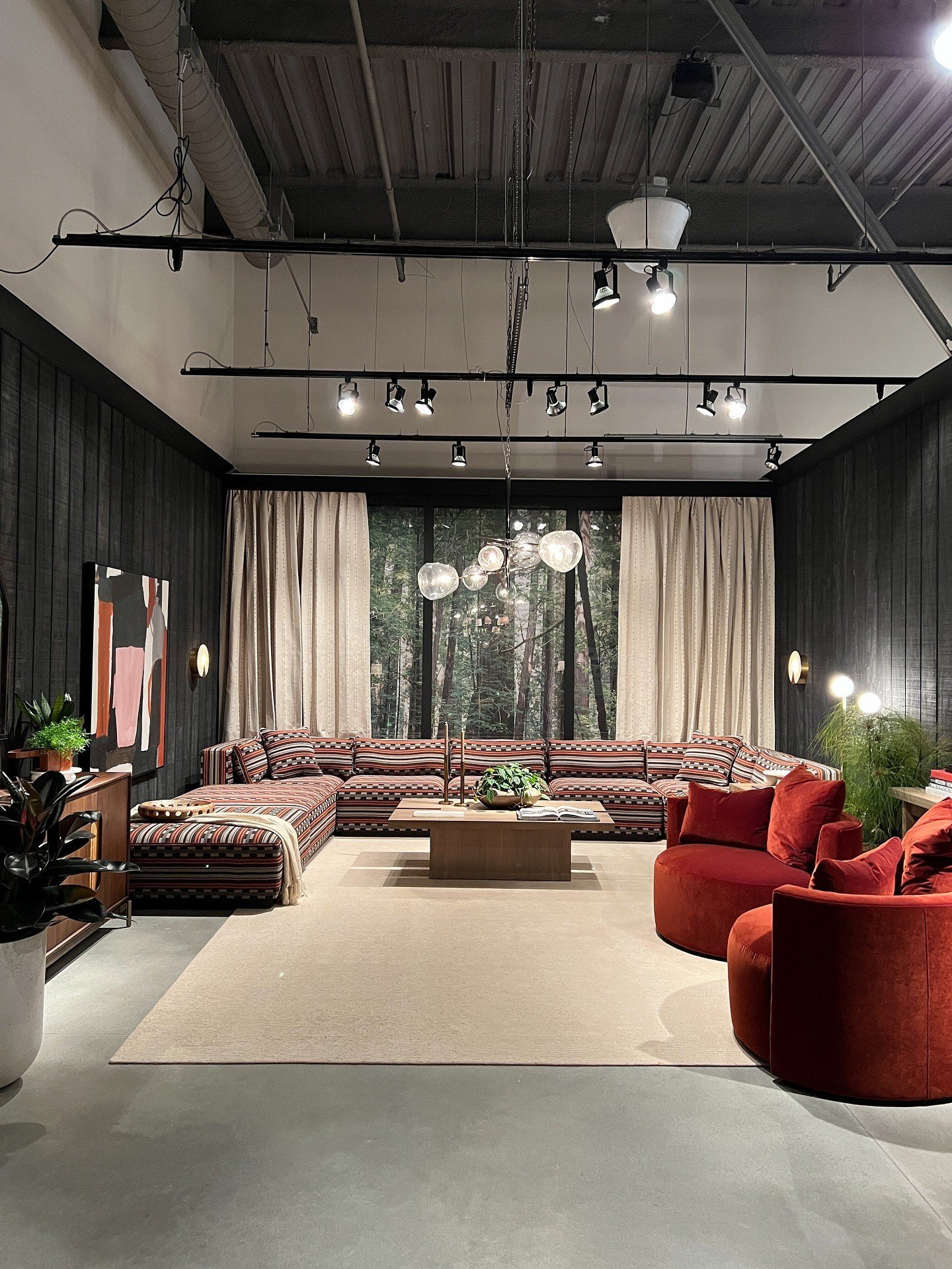Wide showroom view with patterned sectional and red curved chairs