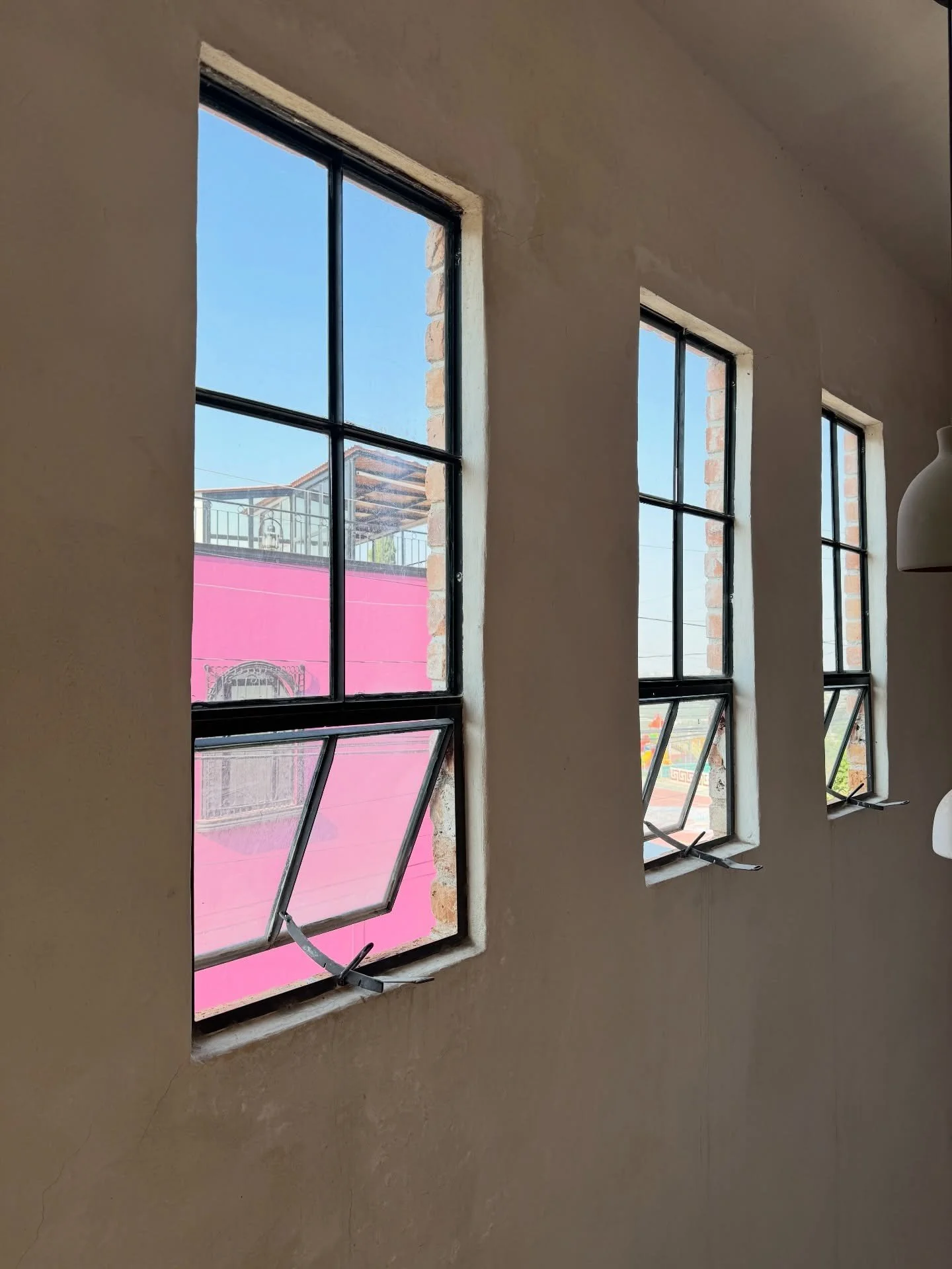 Black steel windows above a sunlit showroom floor